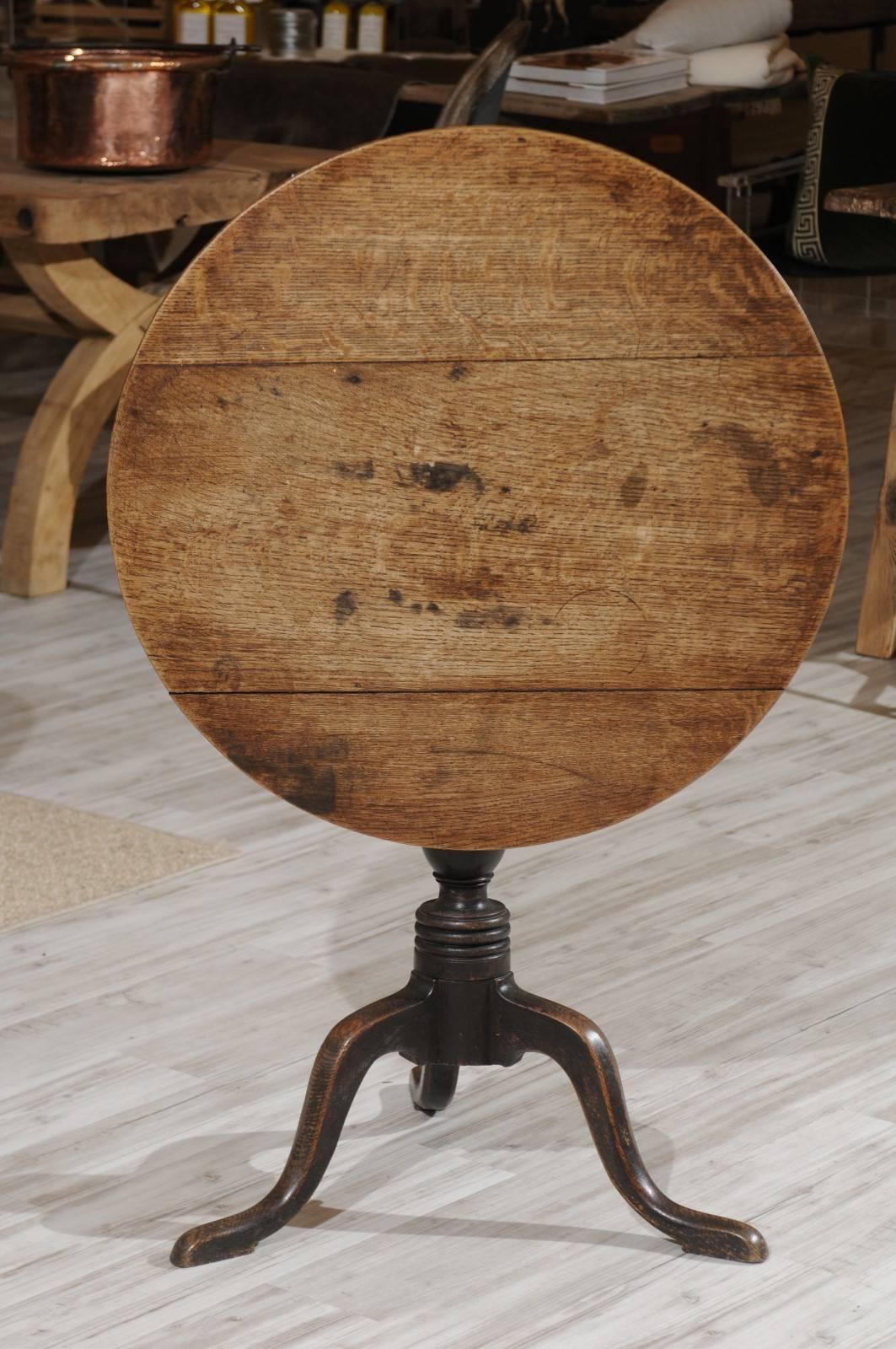 A 19th century French oakwood rustic guéridon table with circular tilt top, raised on a turned pedestal with tripod base. We loved the patina of this French rustic guéridon table, a 19th century oak folding table that looks as functional in its