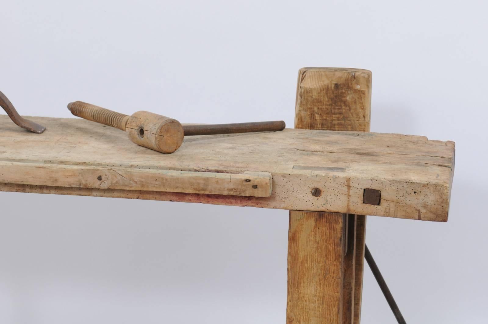 A French établi workbench from the 1920s with solid iron hand crank. This handsome workbench from France has it all: weathered wood with a pale patina, a handsome hand crank in solid iron and an elegant iron brace once used to anchor the wood. Don't