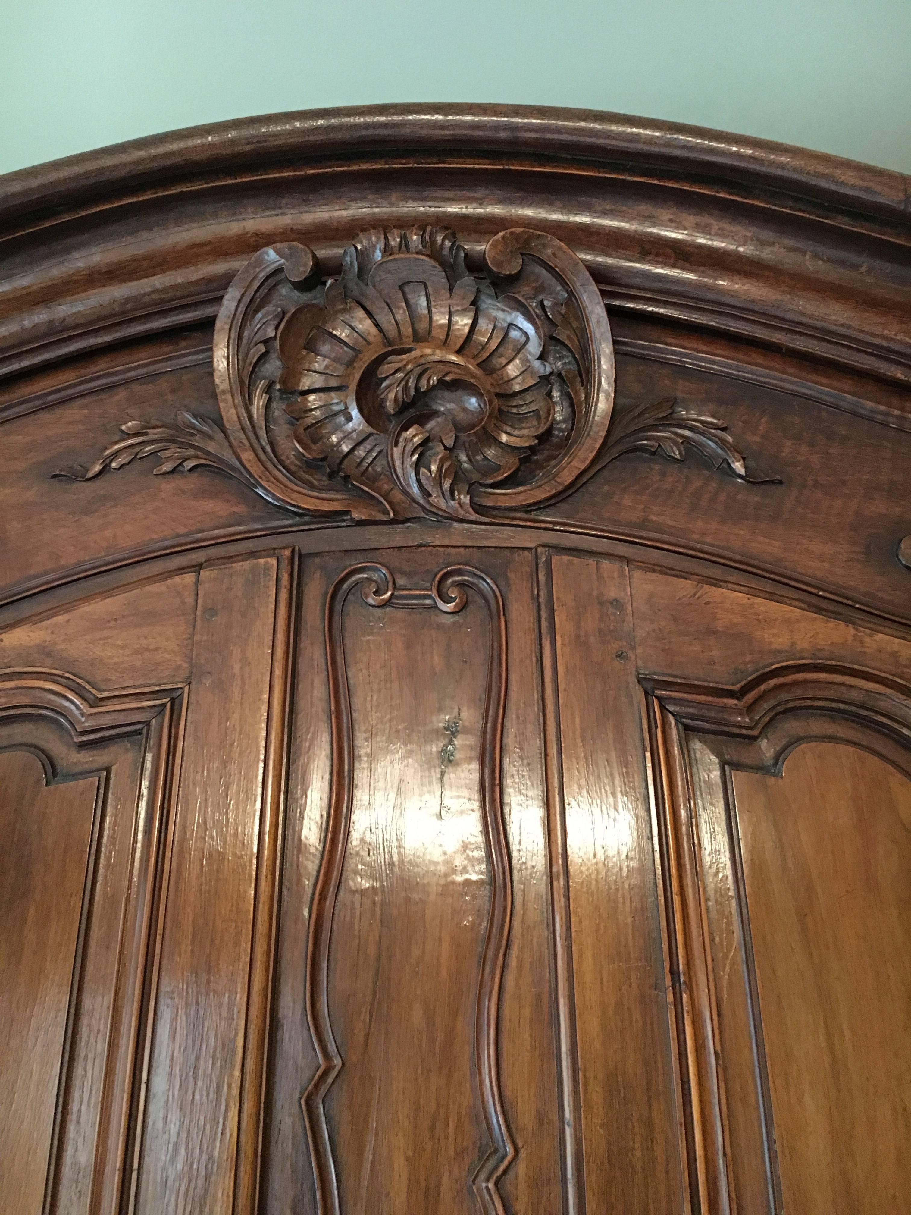 A fine Provençal French Louis XV period walnut armoire of large size and exceptional quality. The armoire is Provençal in protein, and dates from the mid-1700s. The armoire features an arched cornice with central cabochon design and a pierced apron