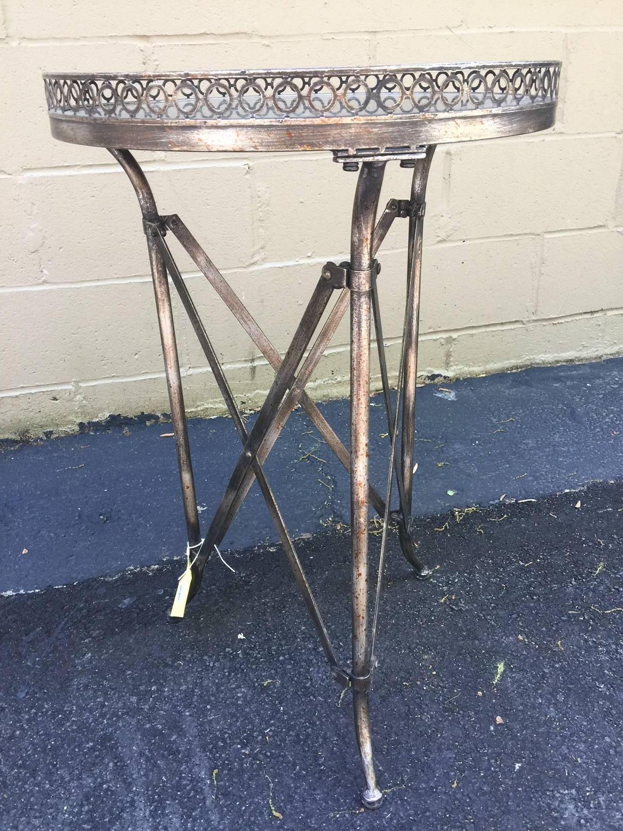 A Napoleon style French guéridon side table from the mid-20th century. We adored this Napoleon-inspired side table the second we saw it. It is made of an iron X-frame, supporting a circular gray marble top. The latter is adorned with an exquisite