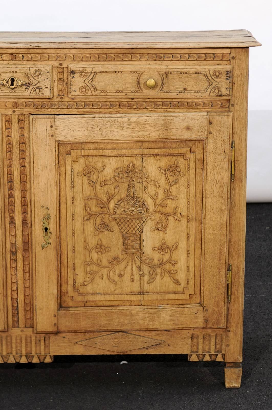 This Louis XVI style carved and stripped oak buffet from the mid-19th century features a rectangular top with canted edges in the front, over three drawers grooved on the side for the runner and two doors. Born in Belgium, this is one of the most