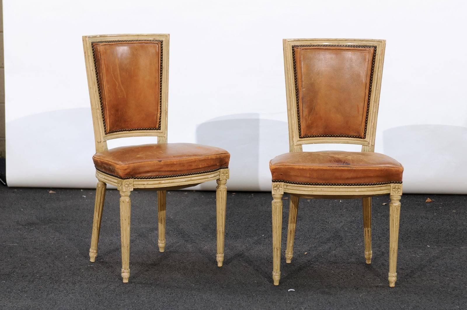 This set of four French Louis XVI style dining chairs from the mid-20th century features the typical neoclassical décor inspired by antiquity so dear to the Louis XVI era, framing delightful leather seats and backs. We're not sure if it was the