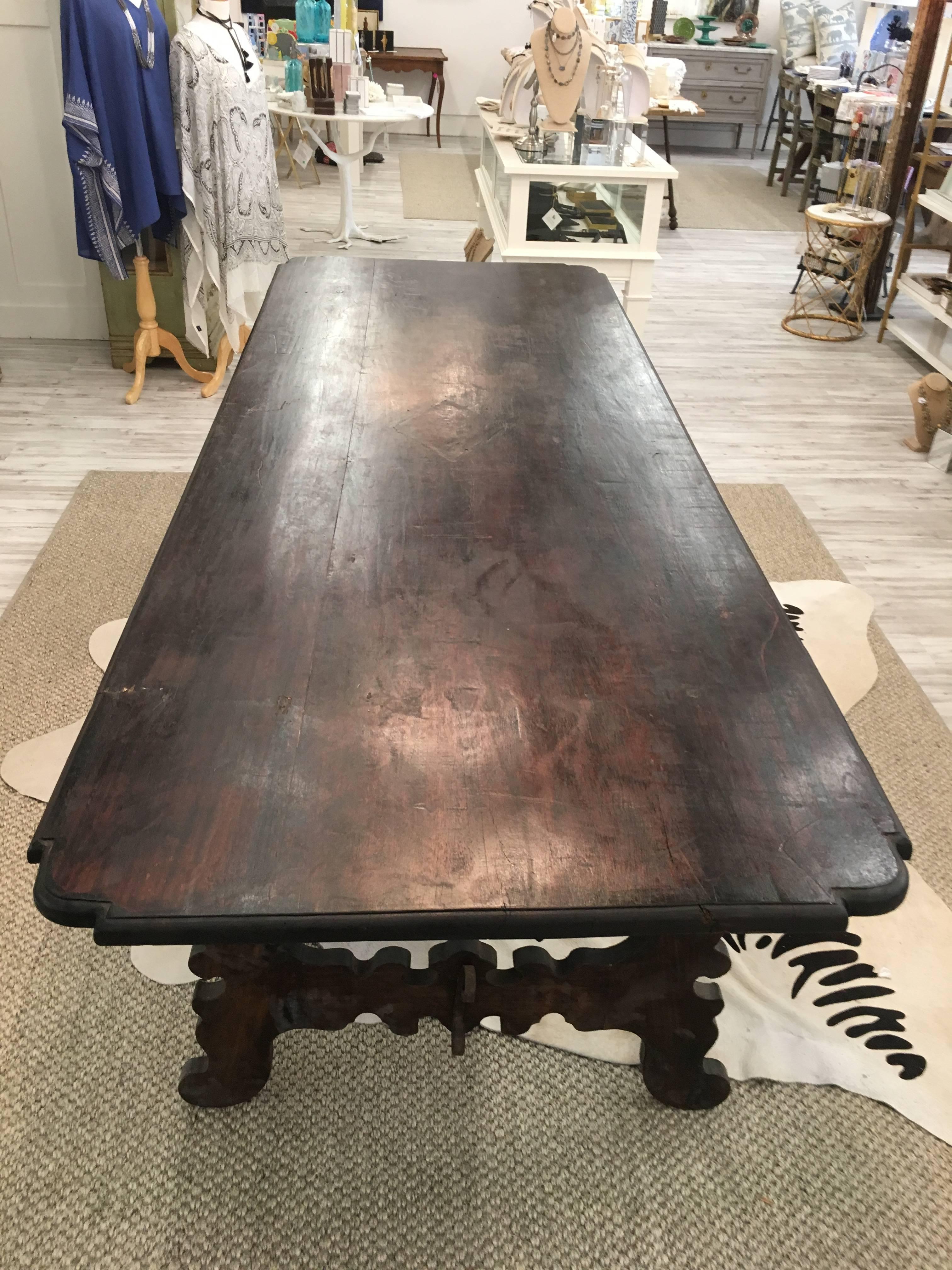 This Italian dining table from the late 19th century features a rectangular top with nicely carved rounded corners over an exquisite Baroque style trestle base with lyre shaped legs. Made of dark wood with wonderful lines, this fabulous table came