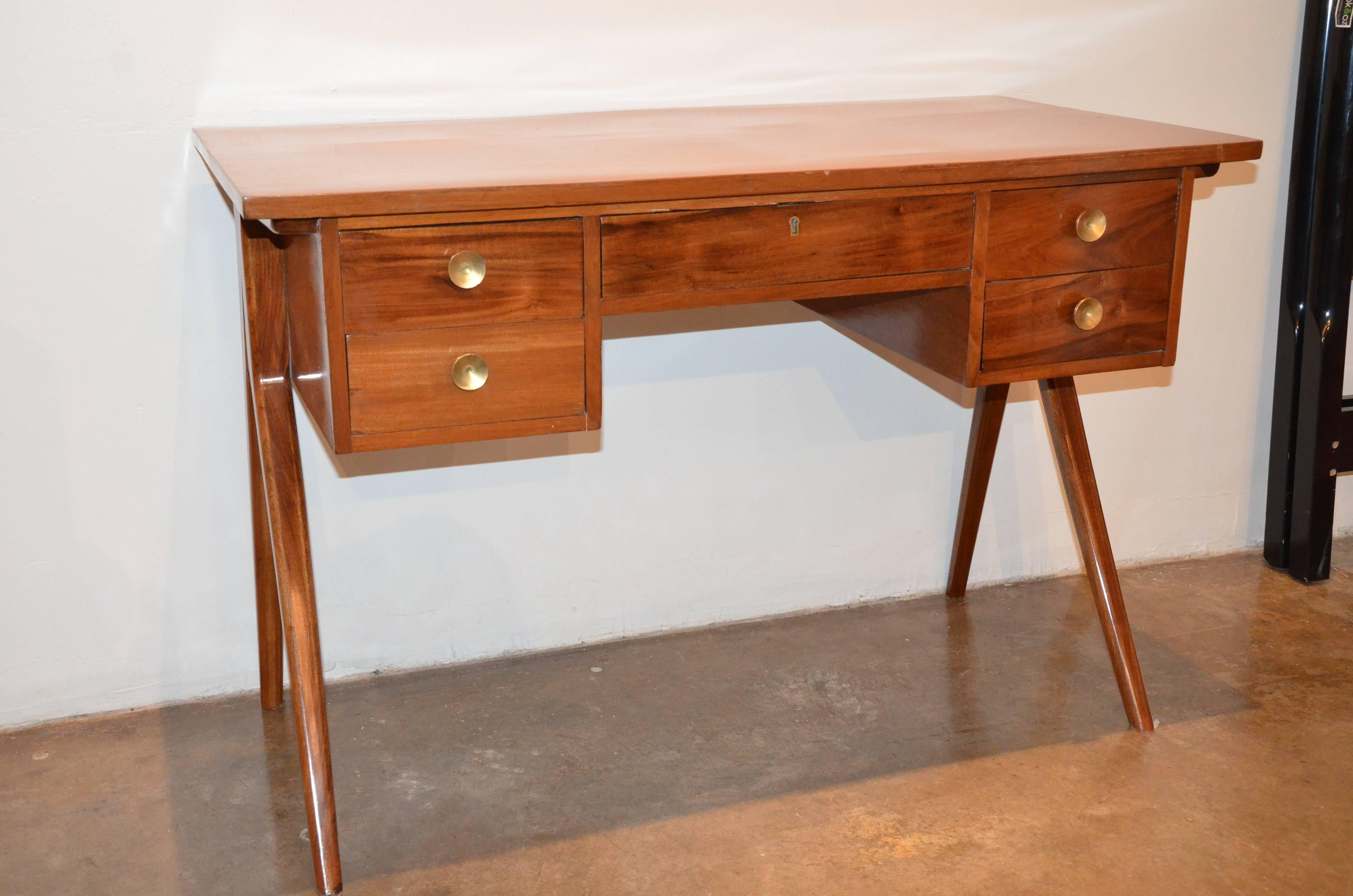 Offered is a mid century modern Argentinian desk or writing table with brass pulls. 
 This Argentinian gem is made from beautiful Argentinian Lignum Vitae wood and oversized brass pulls. This writing table has Classic Mid-Century lines that would