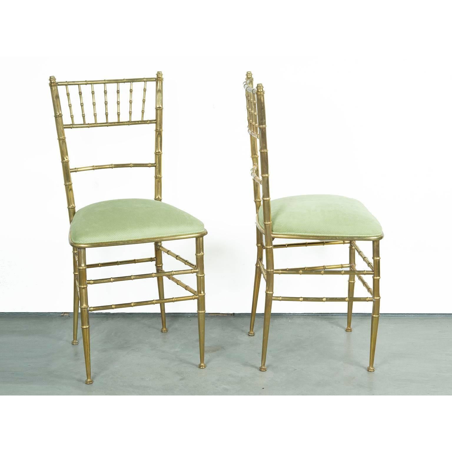 Offered is a pair of Mid-Century Modern Italian brass Chiavari faux bamboo style armless chairs that have been updated with a warm tone moss green velvet / velour fabric that glamorously compliments the brass chair. This petite pair would look