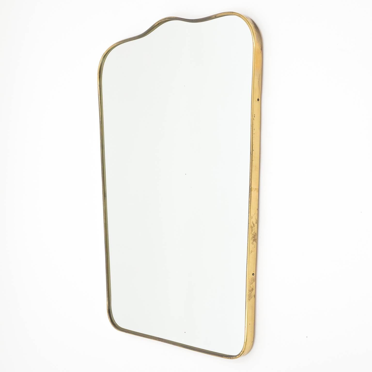Elegant Gio Ponti style brass mirror from the 1950s. Has a nice patina on the brass and a few minor age-related specks in the mirror. Measuring width on the bottom is 18.5inches/47cm.