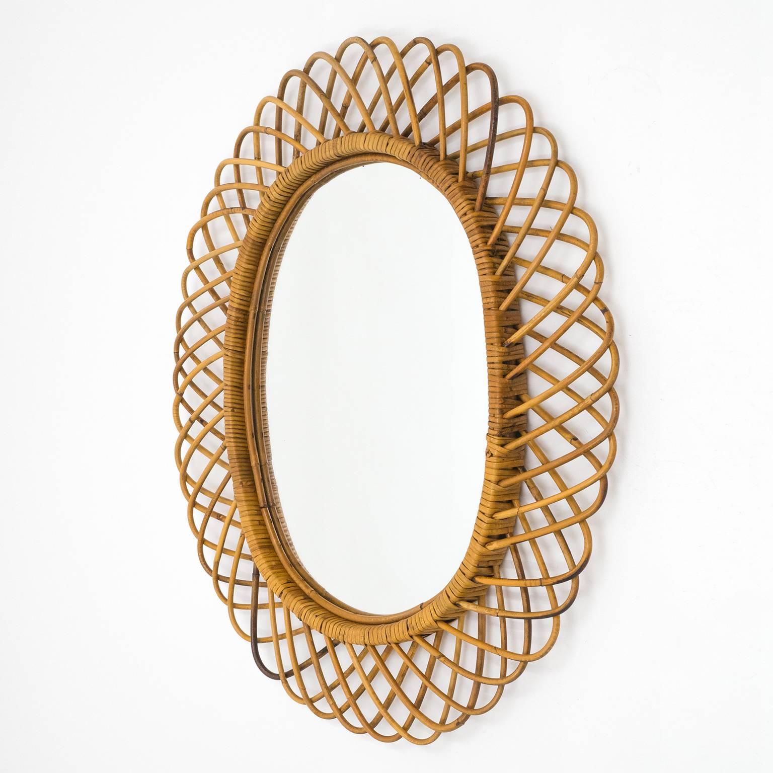 Lovely oval rattan mirror from the Italian Riviera in the 1960s. Very well preserved with all original parts, the rattan and wicker have a lovely warm patina and the original mirror exhibits a few age-related specks and light scratches.