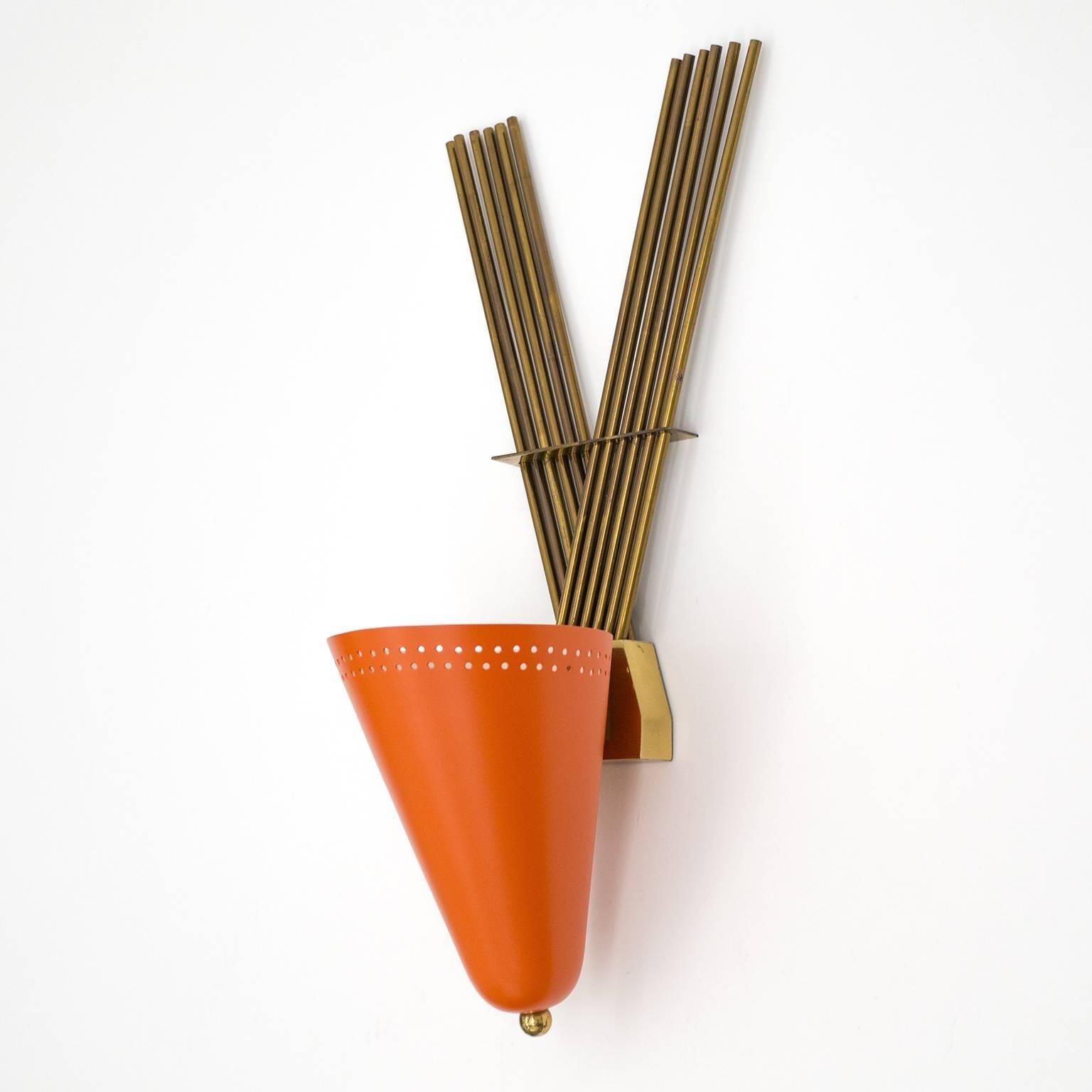 Highly unique large wall light from the 1950s. This unusual up-light features a large laquered and perforated aluminum cone against a backdrop of 12 brass rods arranged in a large 