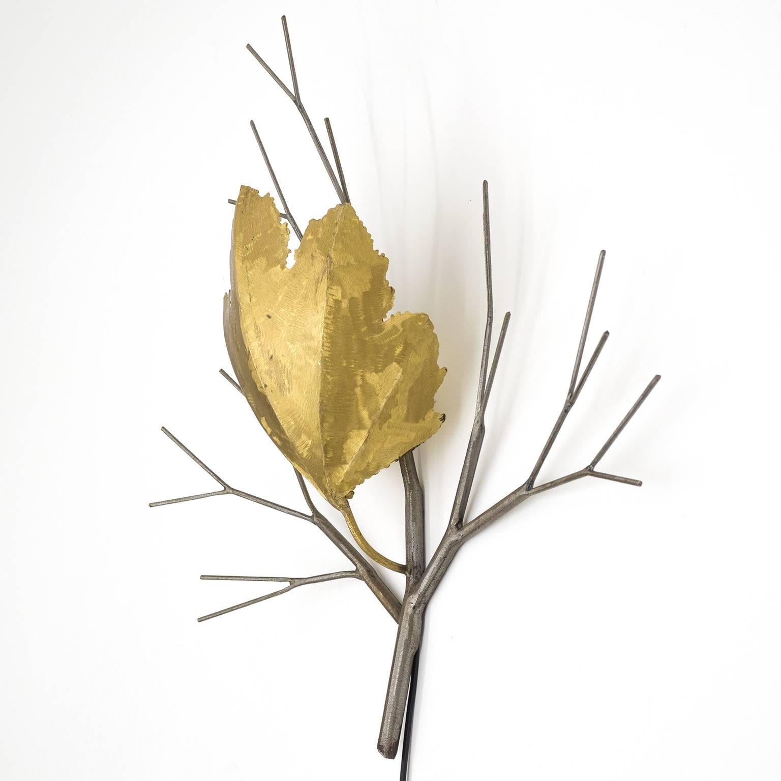 Rare large French brass and steel wall light, circa 1970. A stylized steel branch with a large torch-cut brass leaf which envelopes around a single brass and ceramic E14 socket with new wiring. Very unique design pairing rough surface handling
