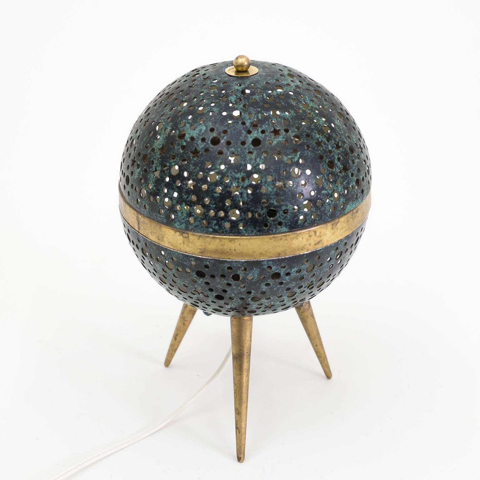 Delightful little mood table lamp from France, circa 1950. The pierced aluminum globe is covered in tiny circle and star shaped cut-outs and lacquered to resemble patinated bronze. Despite its diminutive size this lamp is an instant eyecatcher due