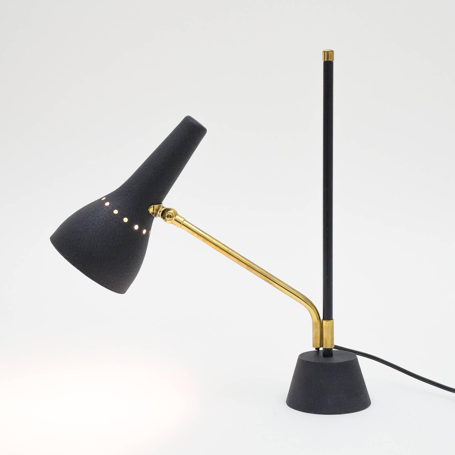 Remarkable modernist desk or task lamp, Germany, 1950s. The articulated brass arm slides up and down and swivels around the weighted Stand without the need of any mechanism. The cast base and perforated aluminum shade are lacquered in wrinkle paint.