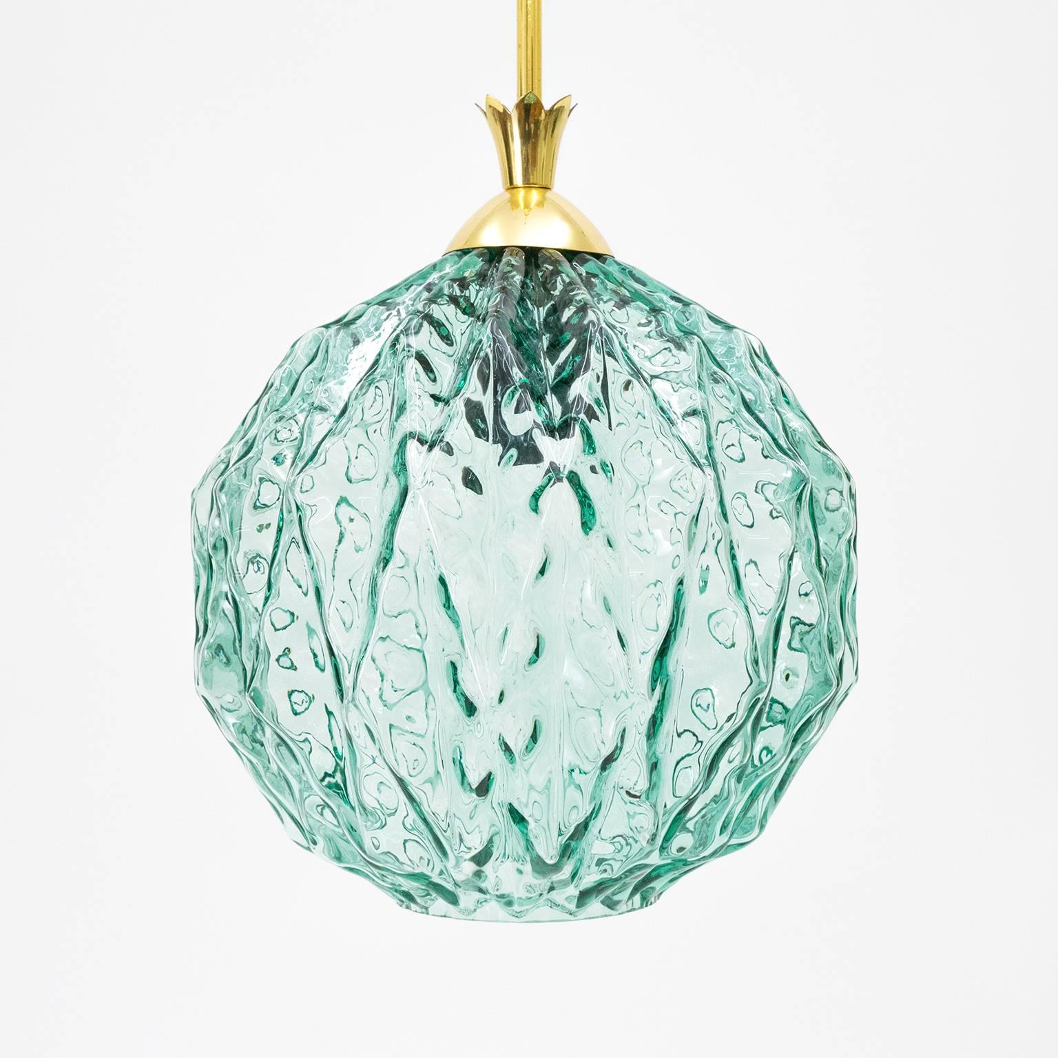 Very distinctive Italian Mid-Century glass pendants with polished brass hardware. The turquoise colored glass has a very unique geometric texture that appears to be melting wax-like. Highly unusual items that definitely stand out. One E27 socket