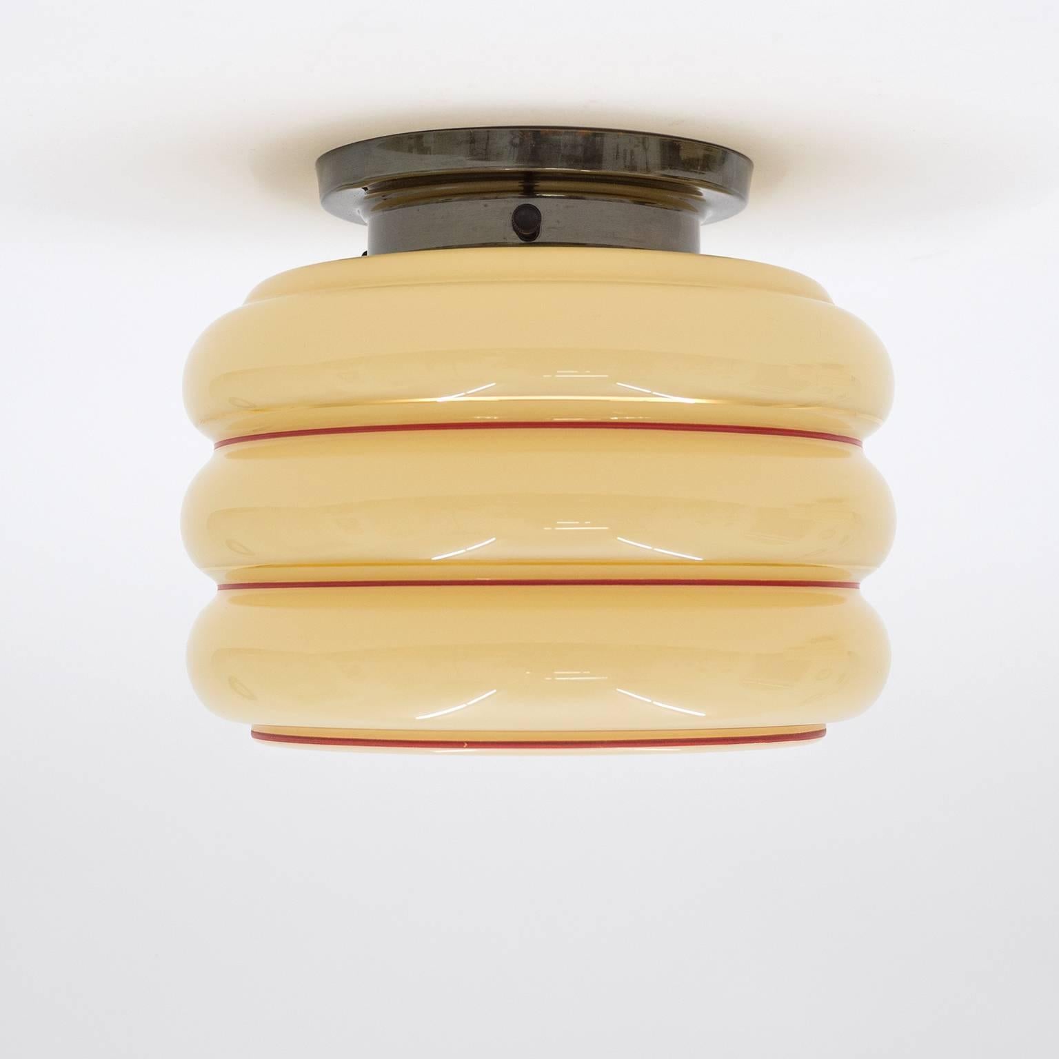 Lovely Art Deco flush mount from Sweden, 1940s. The blown glass is cased in a cream color with red and gold rings painted to the outside. The base is patinated brass and has one original brass E27 socket. Beautiful original condition with minor wear