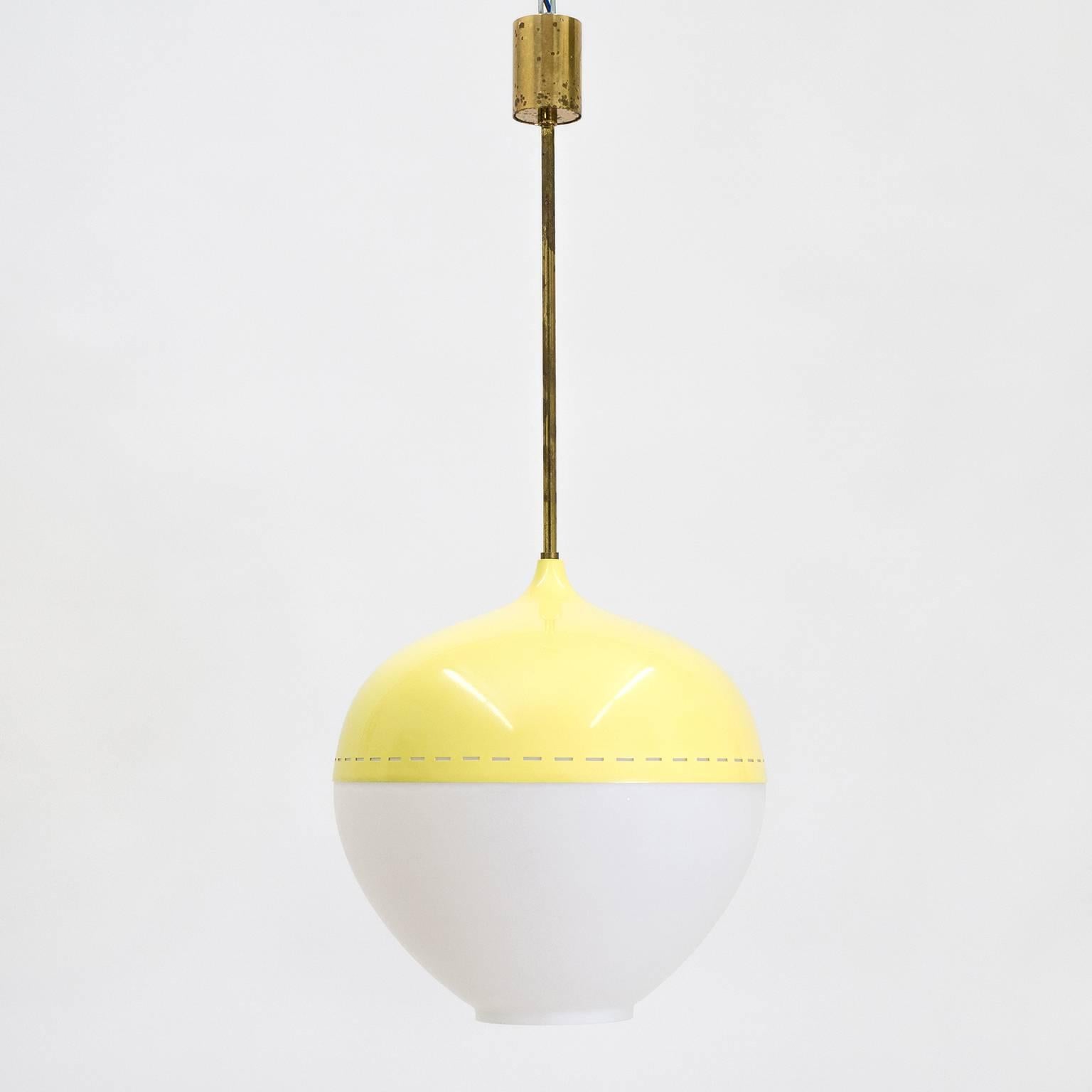 Rare Stilnovo pendant from the 1950s. A large onion shaped satin glass globe is partially covered by a pierced and lacquered aluminum shade and mounted on brass hardware. The shade has a pastel yellow color with linear piercings along the edge for a