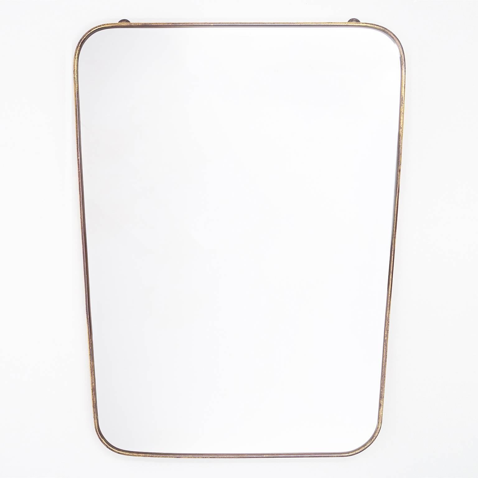 Classic Gio Ponti style Italian brass mirror from the 1950s. A lean, tapered design with rounded corners this mirror has its original silvered mirror in wonderful condition paired with a charming patina on the brass. Width at the bottom is