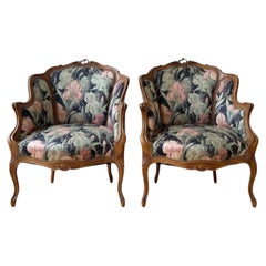 Par de sillones bergère de nogal tallado al estilo Luis XV, con tapizado floral, década de 1950