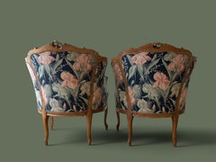 Par de sillones bergère de nogal tallado al estilo Luis XV, con tapizado floral, década de 1950