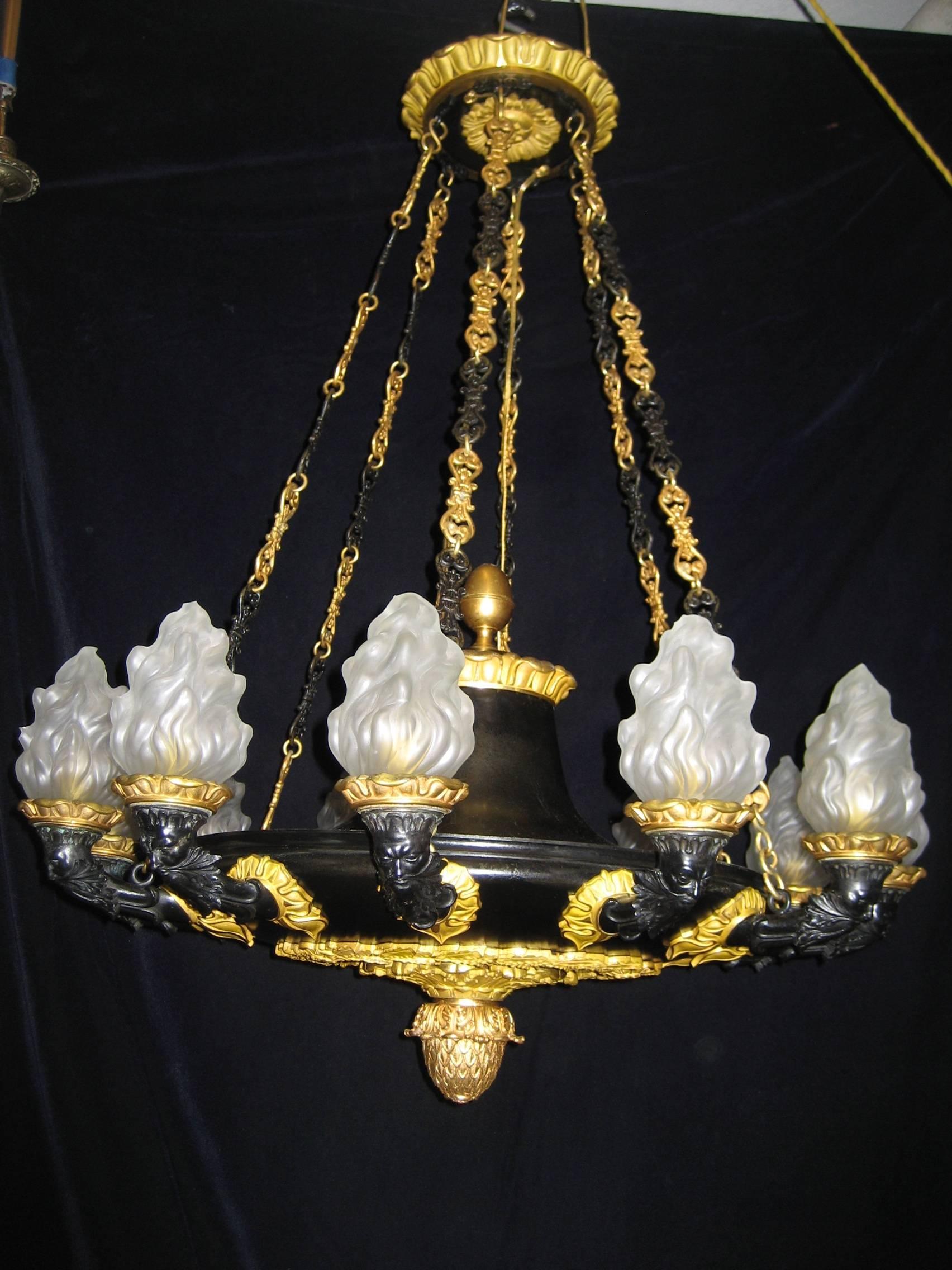 A spectacular and large antique French Empire style gilt bronze and patinated bronze multi light neoclassical chandelier of great detail embellished with neoclassical motifs and further adorned with figural masks.