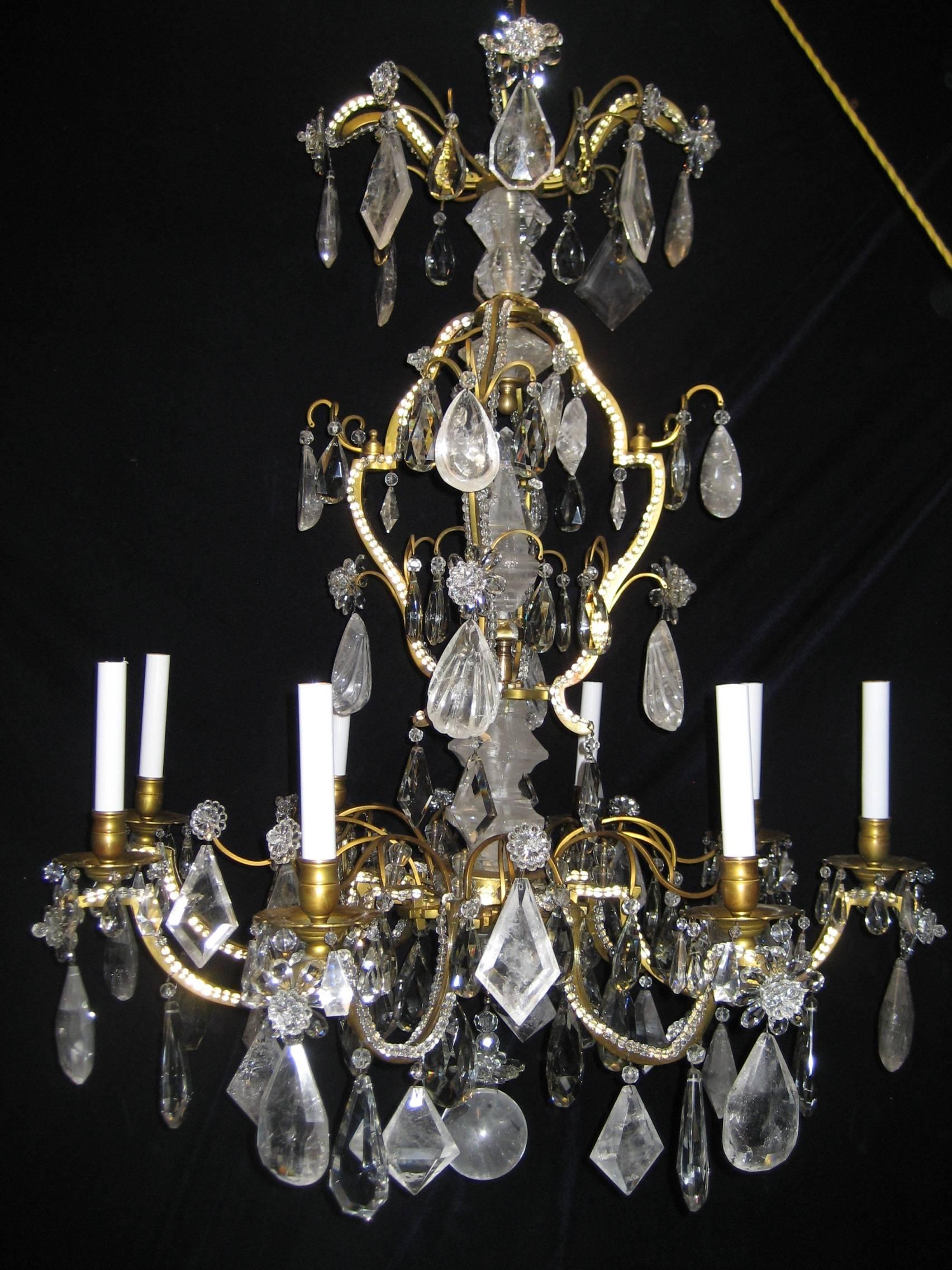 A superb and large antique French Louis XVI style gilt bronze, cut rock crystal, beaded crystal and cut crystal chandelier embellished with cut rock crystal prisms, cut crystal prisms and adorned with a large cut rock crystal obelisk by Baguès,