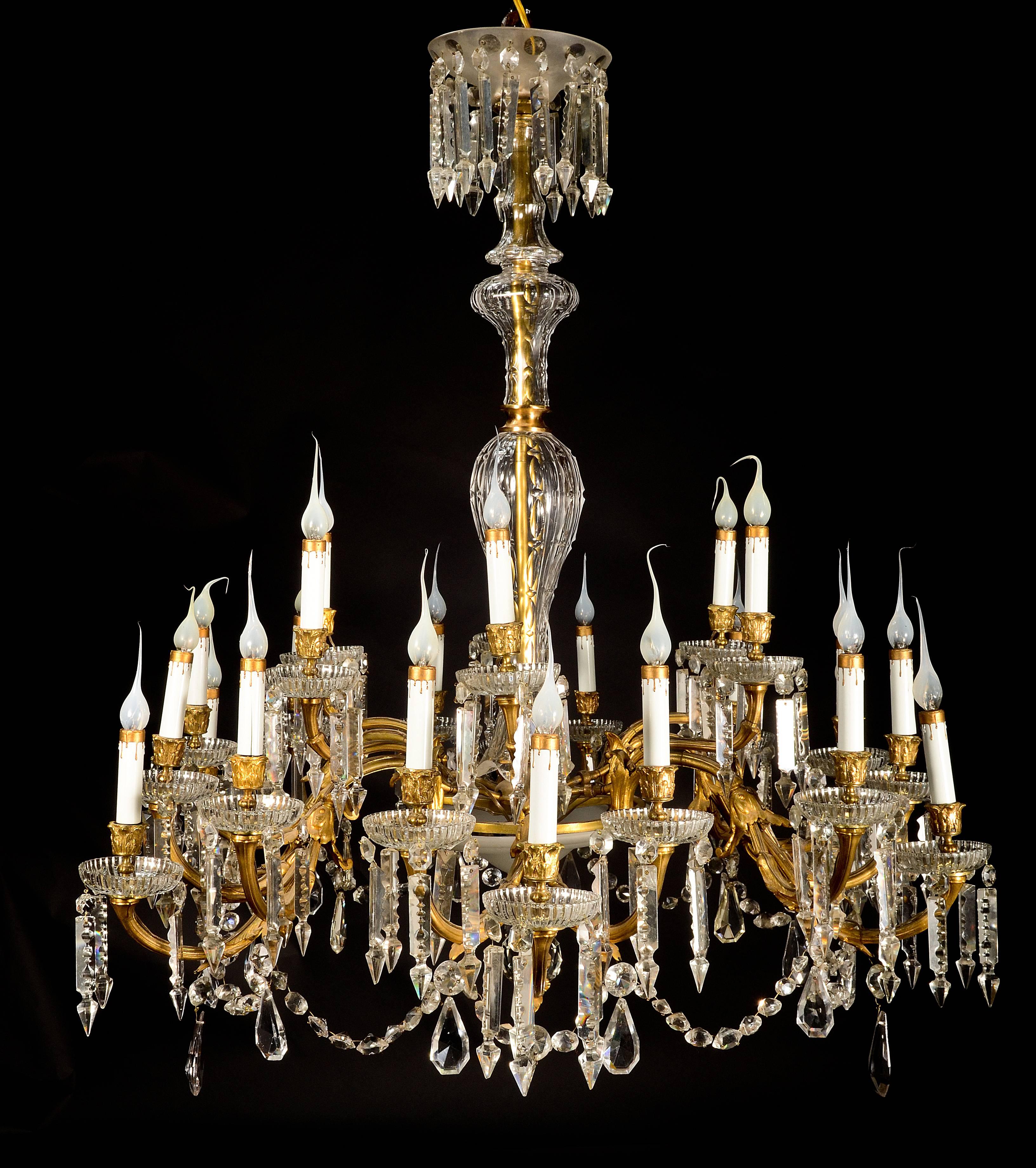 Un grand et superbe lustre ancien de style Louis XVI en bronze doré de Baccarat, verre dépoli et cristal taillé, à 24 bras de lumière, de grande qualité, agrémenté de bolbes, prismes et chaînes en cristal taillé et d'un arbre central en cristal