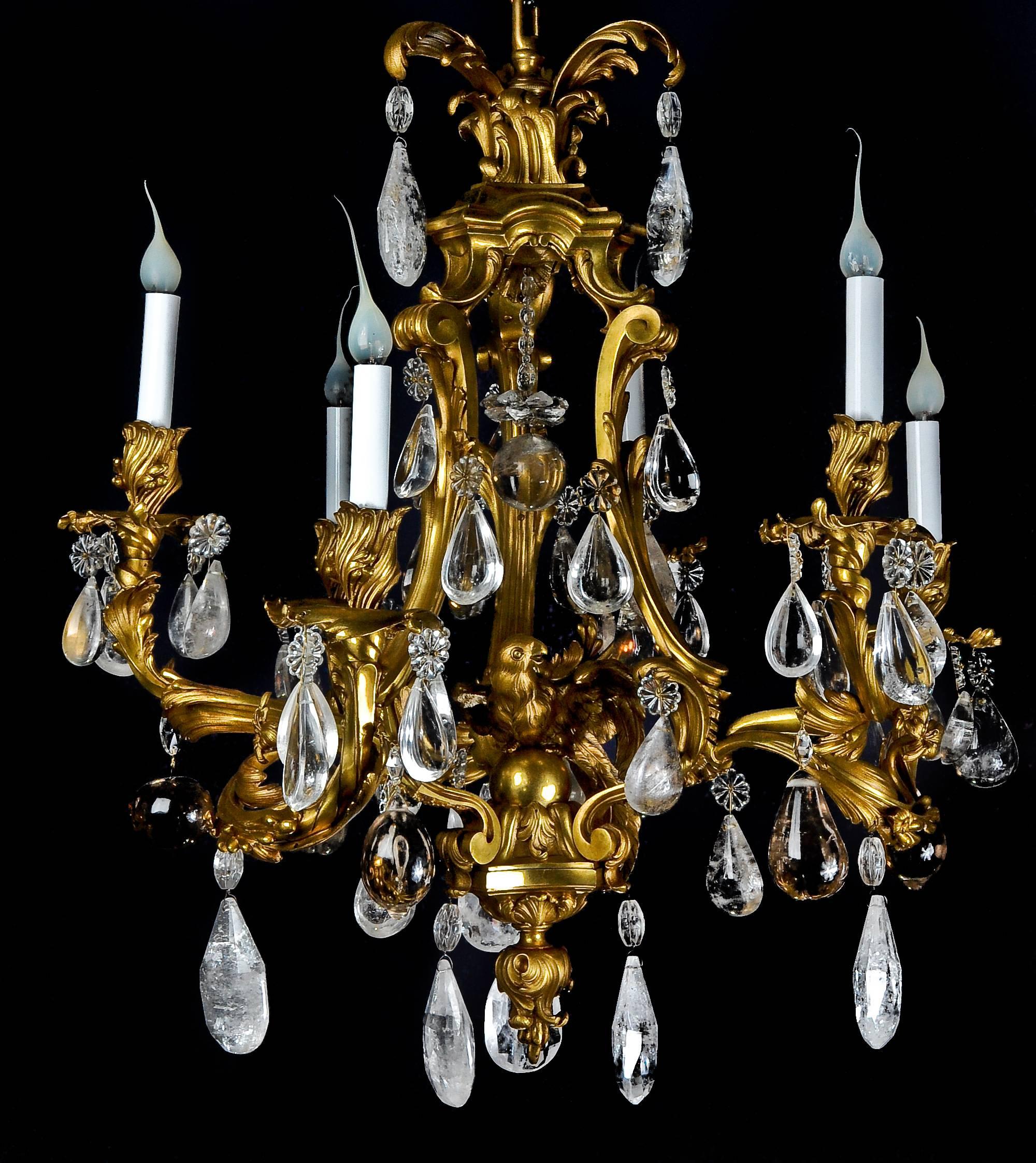 An antique French Louis XVI style gilt bronze and cut rock crystal multi light cage form chandelier of fine detail embellished with a central gilt bronze parrot and further embellished with fine rock crystal prisms.