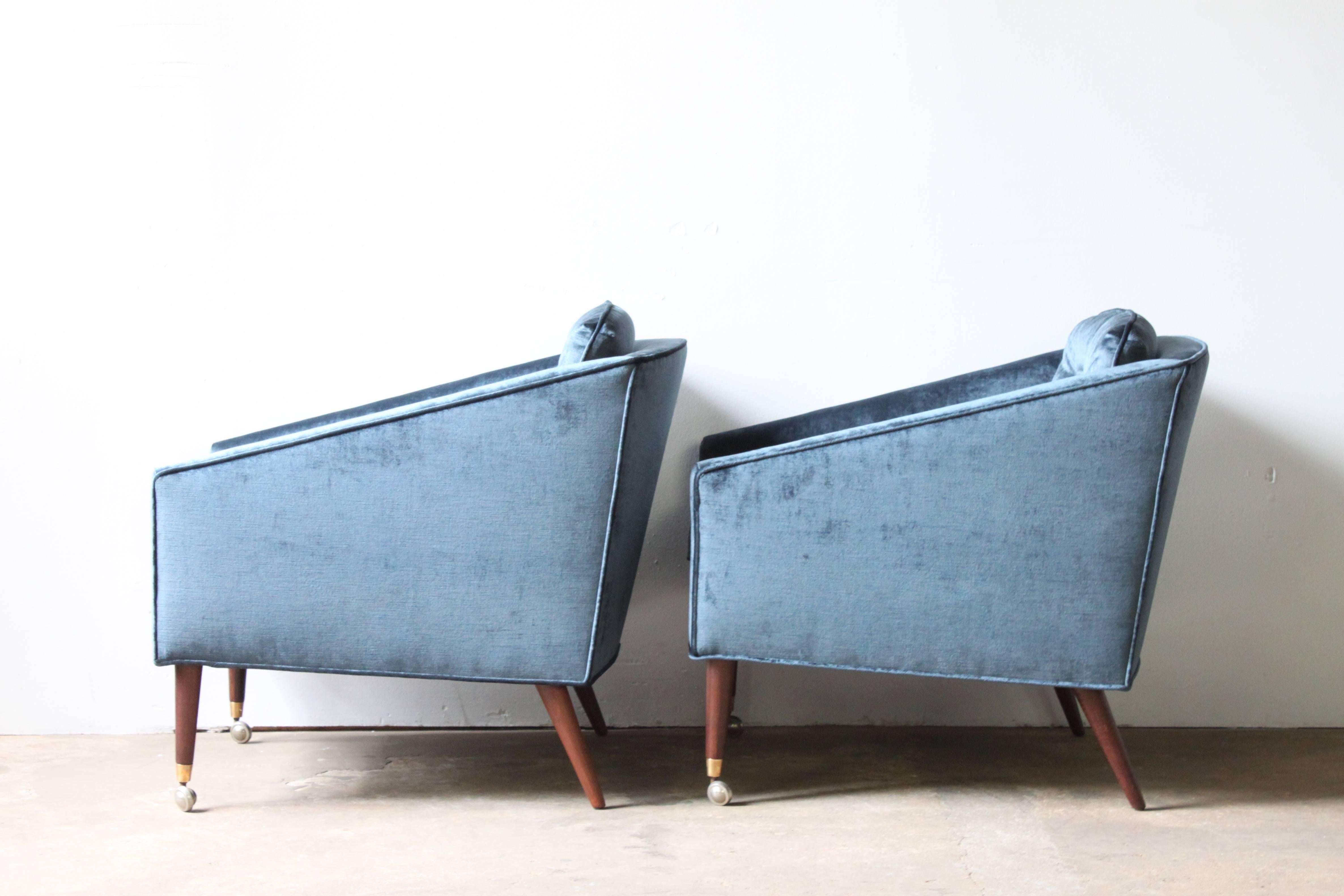 Pair of Mid-Century Italian club chairs. Newly reupholstered in velvet. Tufted seat backs. Walnut legs with brass tips. Front legs include casters.