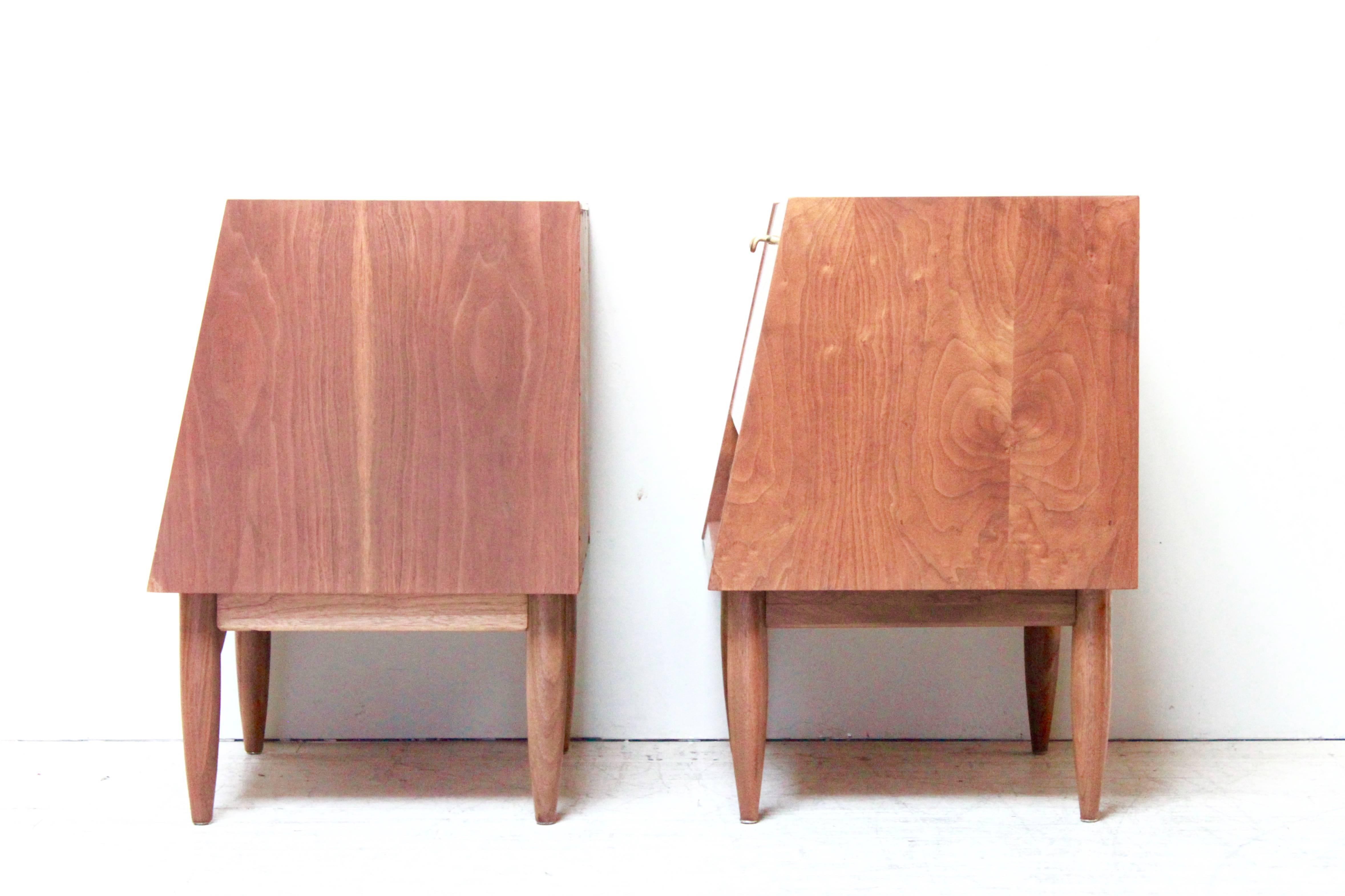 Beautiful restored Martinsville nightstands. Deep rich walnut grain fully envelope both nightstands. They feature brass door pulls. The interiors are also walnut with white laminate inside doors and white lacquer drawers. Designed by Merton Gershun