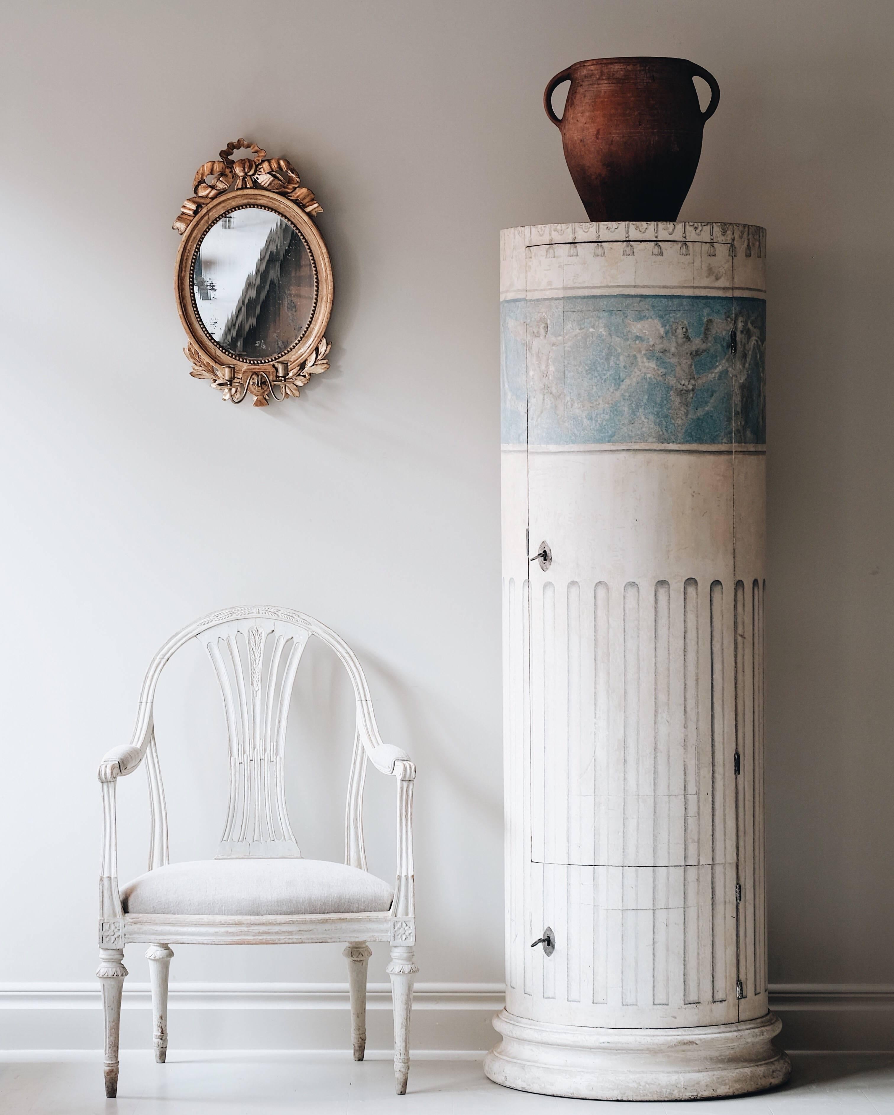 Remarkable and rare late Gustavian period column pedestal cabinet retaining much of it's original color with faux painted flutings and hassles. Two doors with four interior shelves in the top compartment, circa 1815, Sweden.