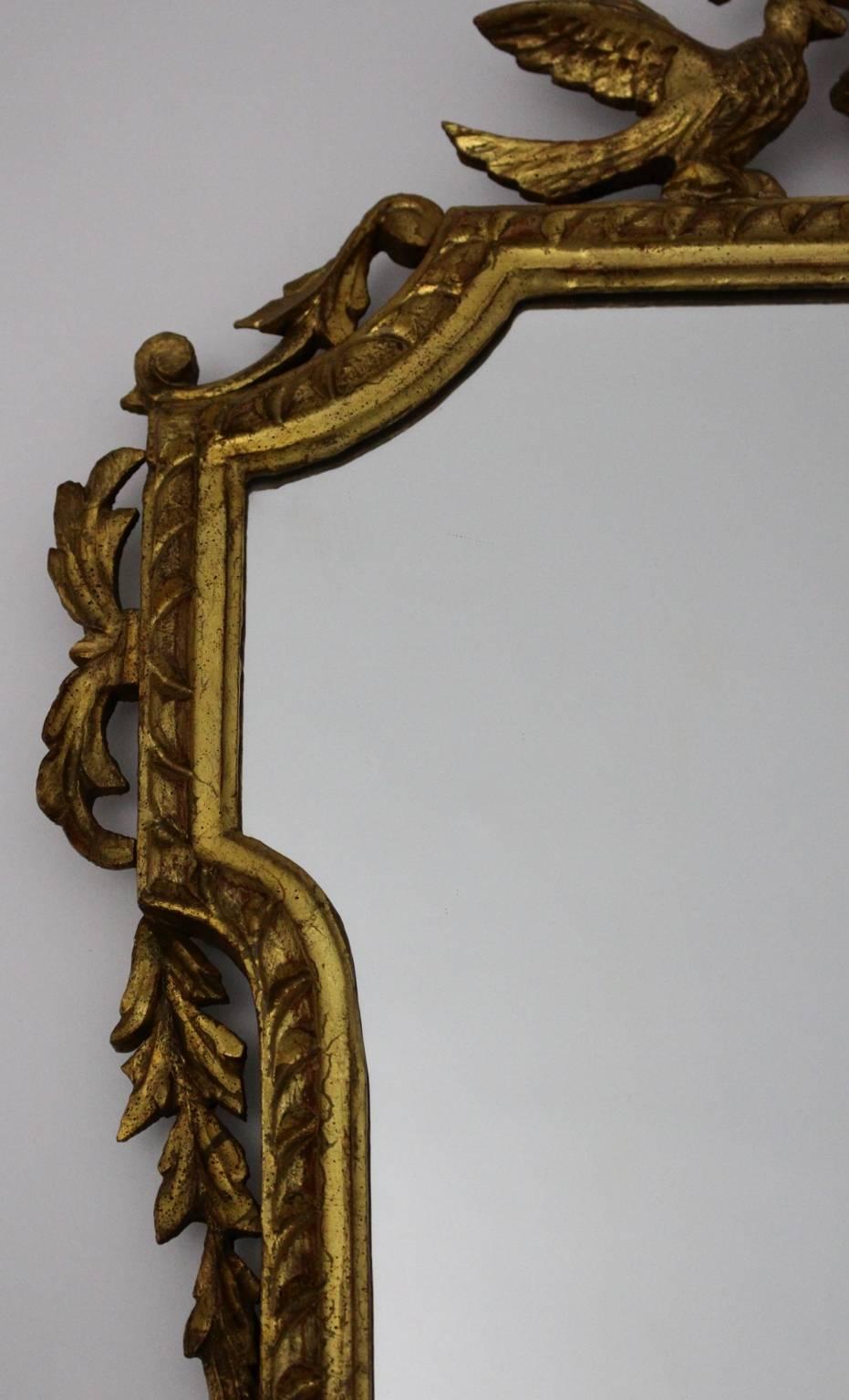 Miroir mural ancien en bois sculpté et doré ou miroir trumeau Autriche circa 1795. 
Le miroir mural vintage / miroir trumeau en bois doré de haute qualité et très décoratif montre des oiseaux et un vase sculptés à la main.
Alors que le miroir mural