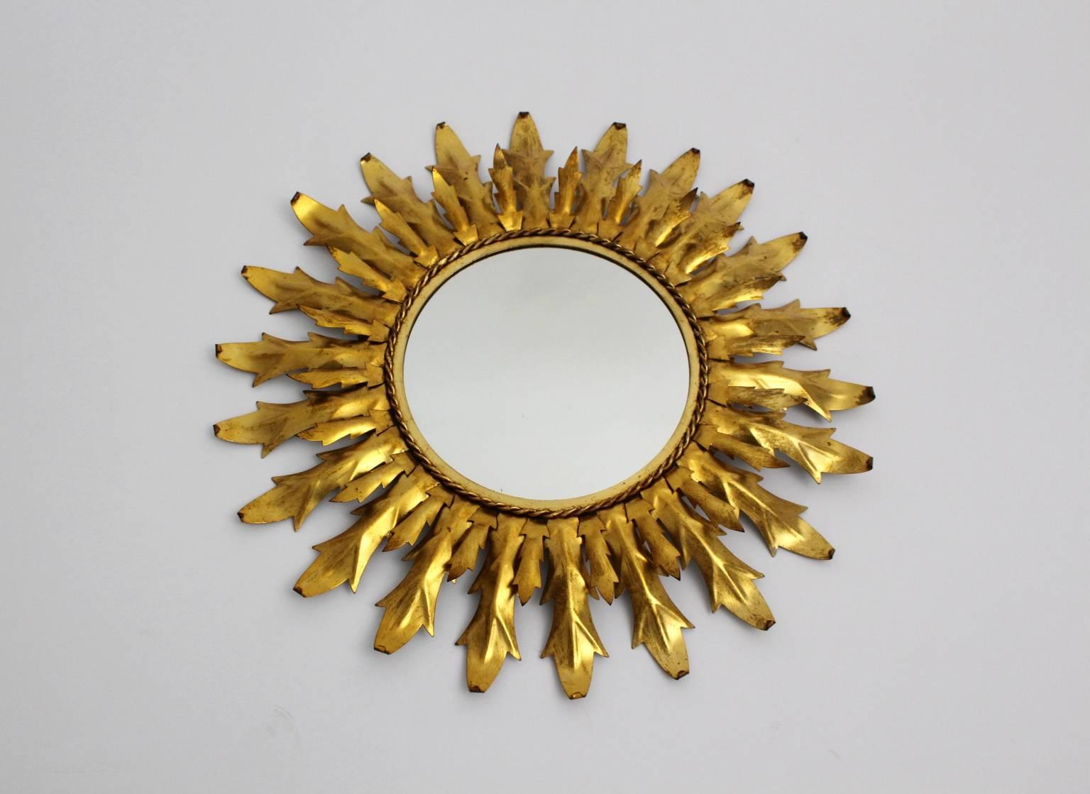 Mid Century Modern gilded metal sunburst mirror or wall mirror with curved leaves, which was made in Italy, circa 1960.
Diameter mirror 11.02 in. (28 cm).
Diameter 25.98 in (66 cm).
Depth 2.36 in (6cm).
 All measures are approximate.