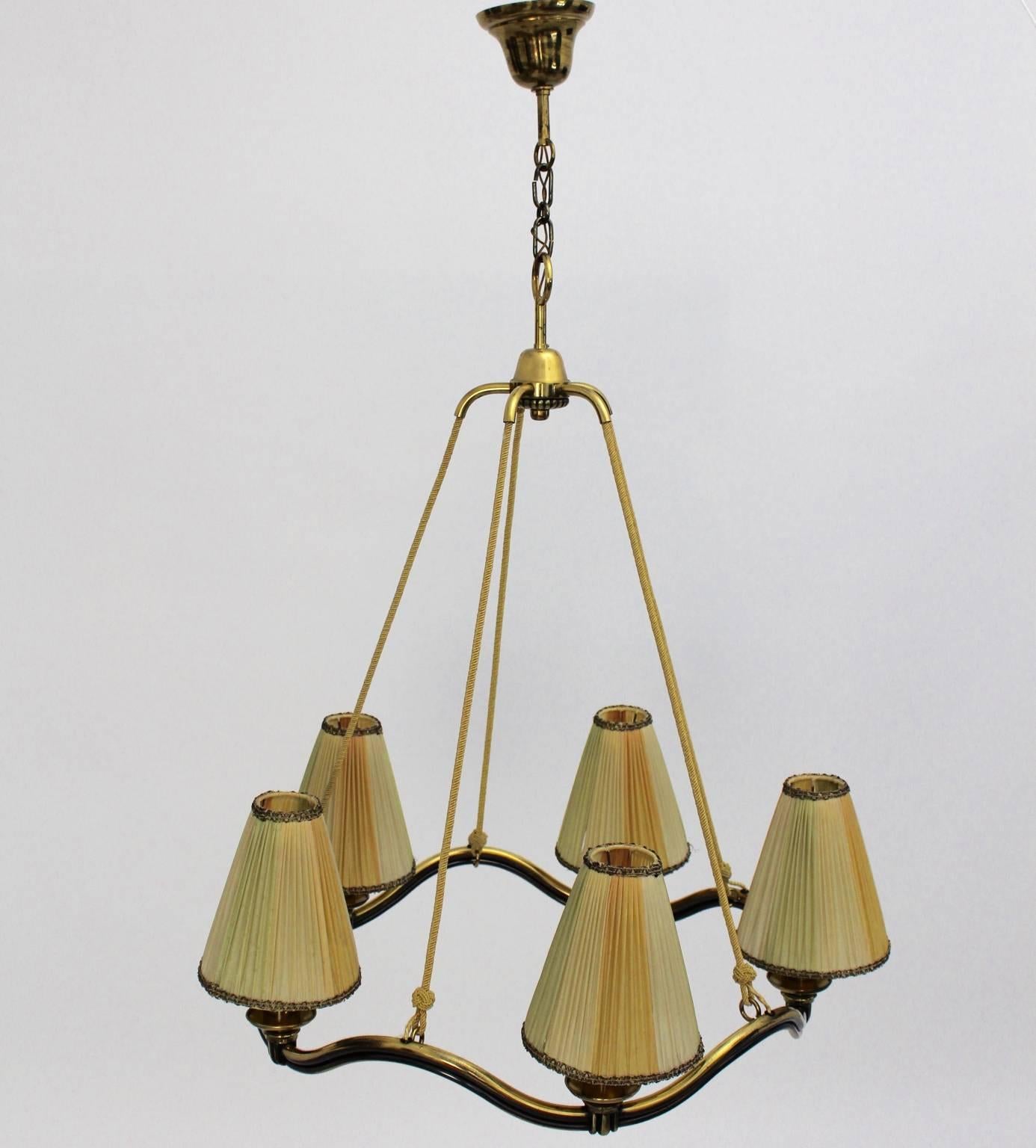 Art deco brass vintage chandelier or fixture, which design is attributed to Hugo Gorge 1930s, Vienna, Austria.
The chandelier shows a wavy line design and the brass tubes are partly stained.
Also the chandelier hangs on five yellow woven strings.