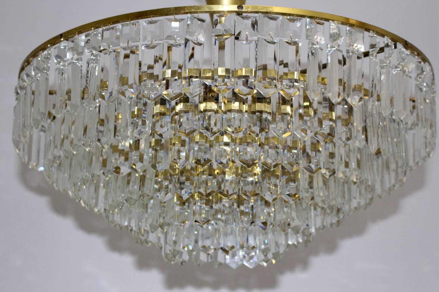 Mid century modern vintage chandelier, which shows hand-cut crystal glasses in squared and rectangular form.
While the two tiered frame was made of brass the chandelier features nine sockets E 27.
The chandelier was designed and manufactured by