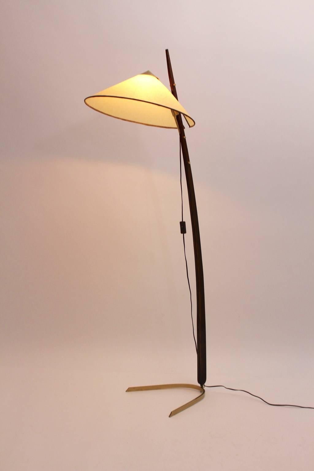 A mid century modern brass floor lamp with a curved stem, which was made out of solid oakwood and a brass foot and brass fittings. On the top sits a parchment paper shade.
The shade is adjustable from up to down in four positions.
One socket E