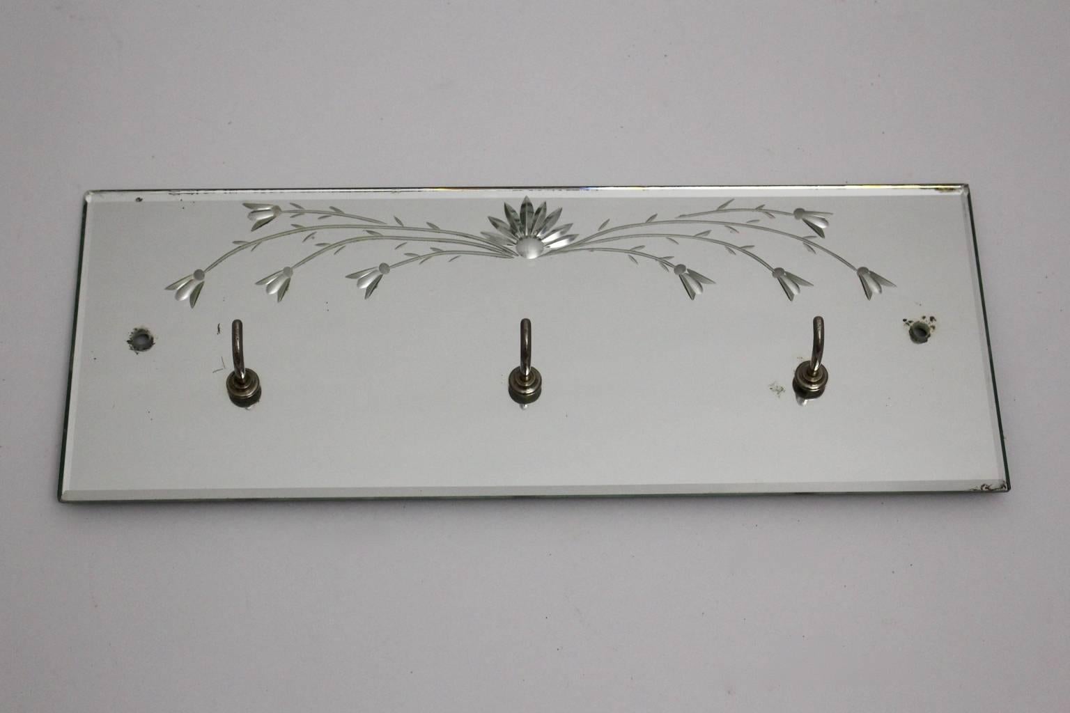 Mid century modern vintage coat rack from mirror glass with etched flowers. While the cute mirror board shows etched flower details, 1950s, Italy the metal hooks are chromed.
Good original condition with minor signs of age and use and with beautiful