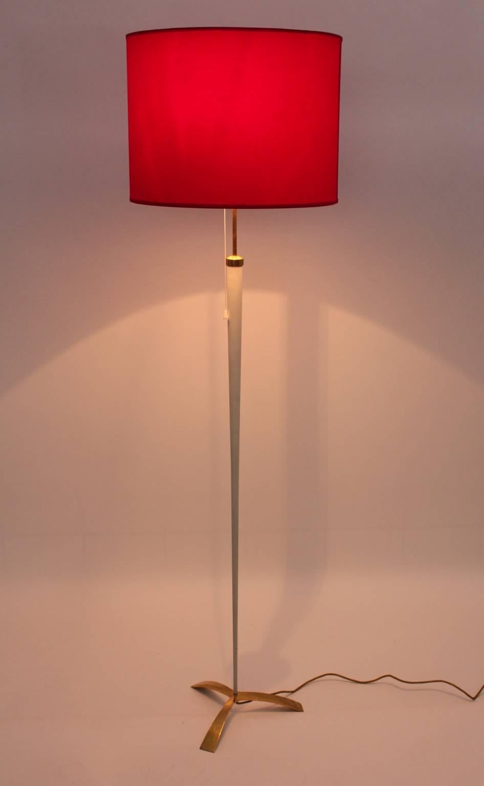 Mid Century Modern vintage floor lamp from metal and brass by Kalmar, Vienna 1950s.
This floor lamp features a brass tripod foot, also brass tube and a conical white lacquered metal stem. 
Furthermore the floor lamp shows two E 14 sockets with a