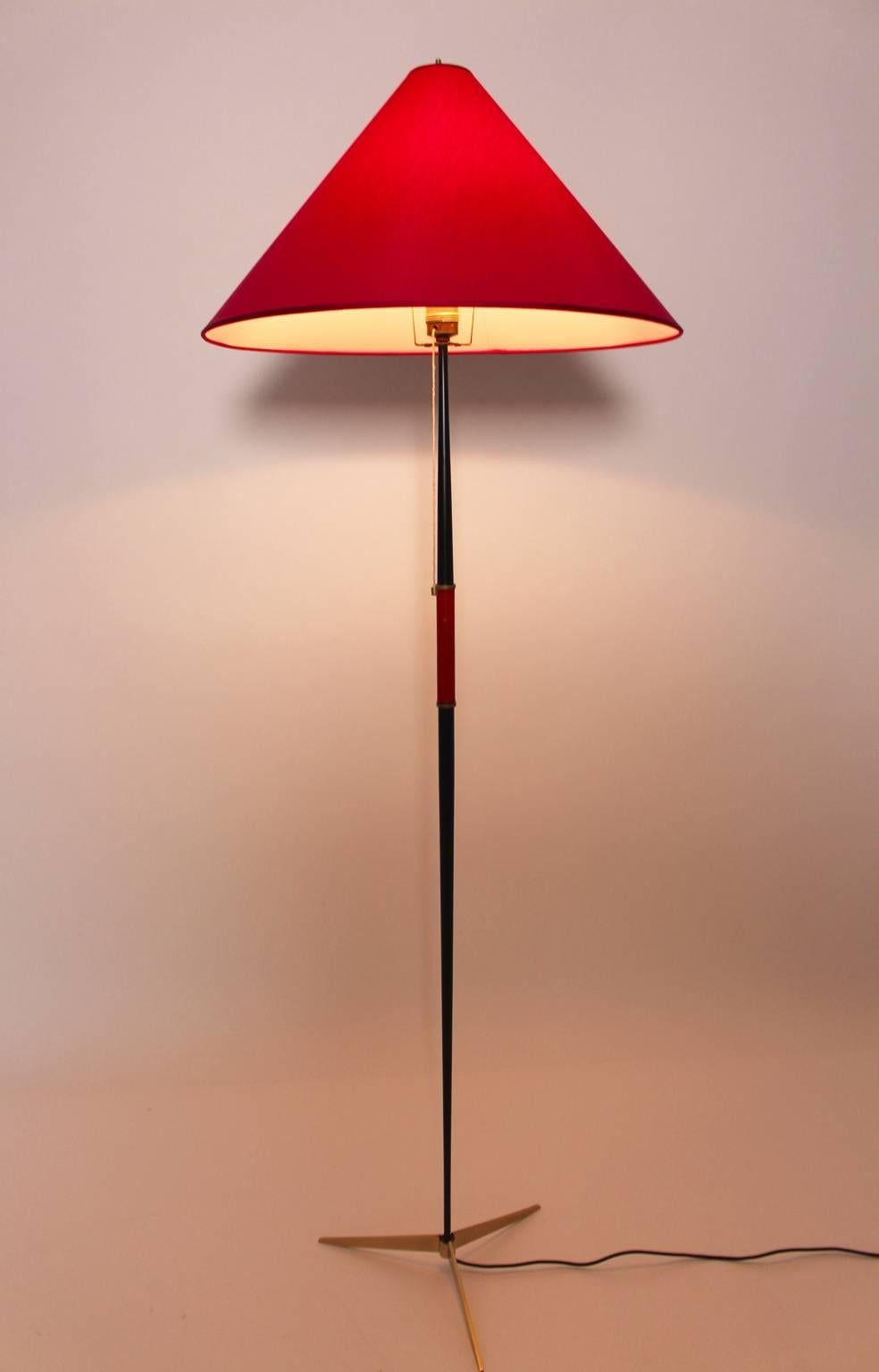 Mid century modern vintage floor lamp designed and executed by J. T. Kalmar Vienna, circa 1960 from brass and metal.
The Floor Lamp consists of a tripod brass foot and a conical black lacquered metal tube. Also the floor lamp features a red leather