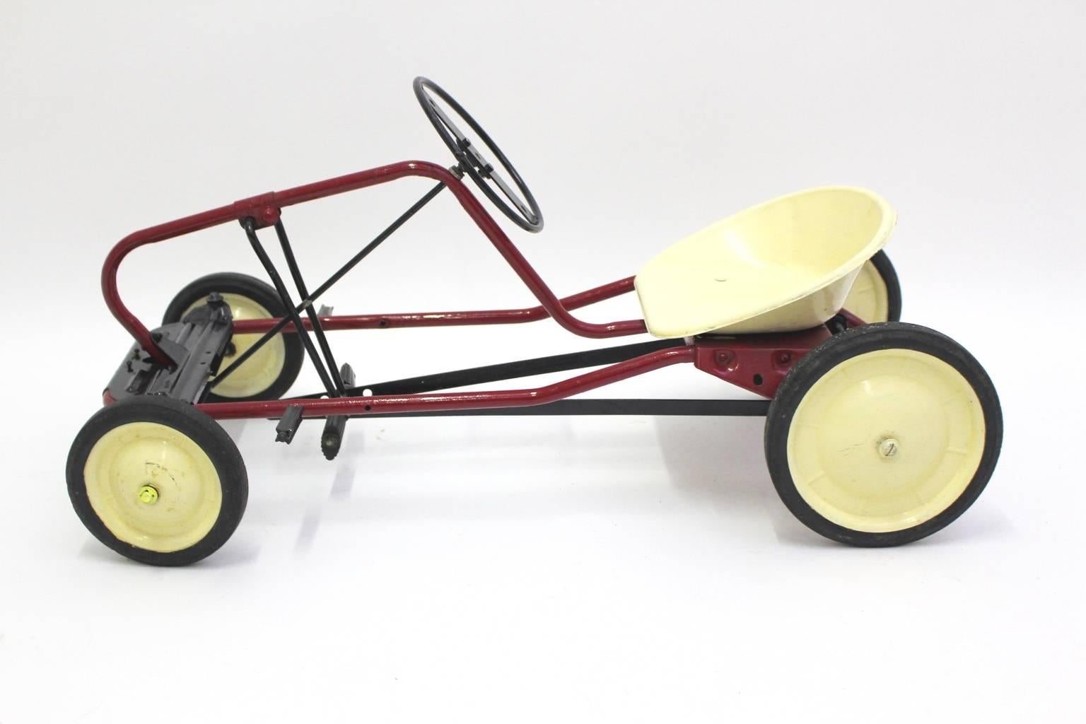 Mid century modern red vintage pedal car, which was made of partially black, red brown and ivory lacquered tube steel base.
An amazing pedal car with  wheels and the pedals from rubber, while the seat shell made from plastic in very good condition,