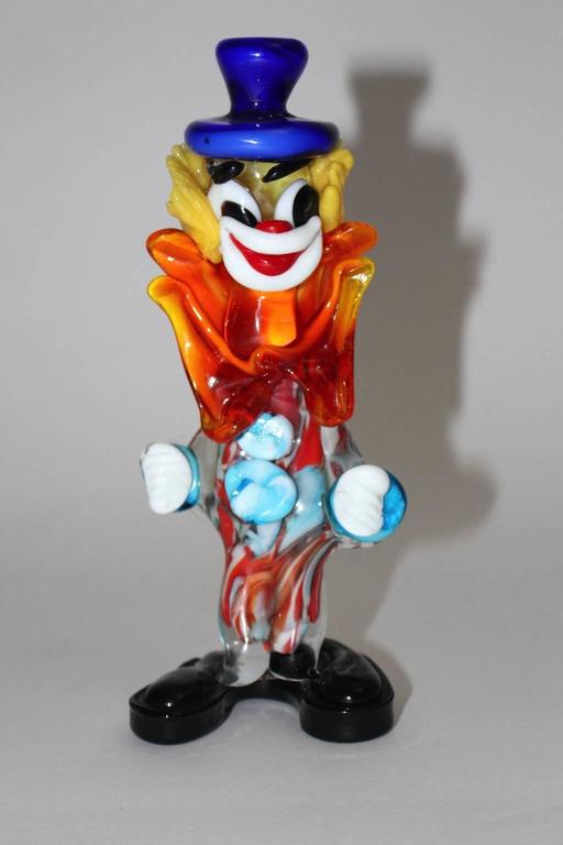 Murano glass clown in the colors blue, red, yellow white and orange. 
Amazing glass clown sculpture designed and manufactured in the Mid-Century Modern era in Murano, Italy.
Very good condition
approx. measures:
Width 8 cm
Depth 7 cm
Height 20
