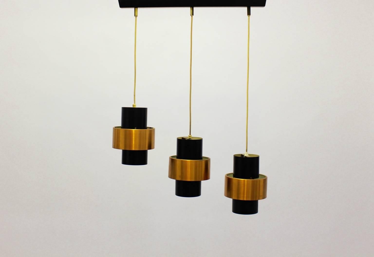 Scandinavian modern vintage chandelier by Jo Hammerborg circa 1960 with three shades shaped like tubes from copper and black lacquered metal.
The shades are fixed with cords on the trail with three fittings for Edison sockets 27.
This chandelier was