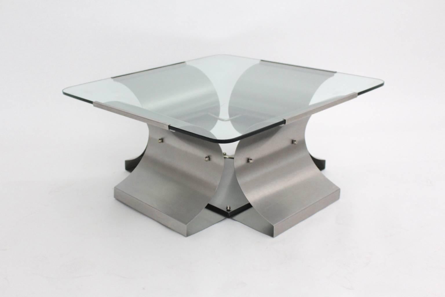 Space Age vintage metal coffee table by Francois Monnet 1970s France, which is a futuristic and extravagant coffee table.
The brushed stainless steel frame is topped with a glass top, which is surrounded and edged with metal clips.
The original
