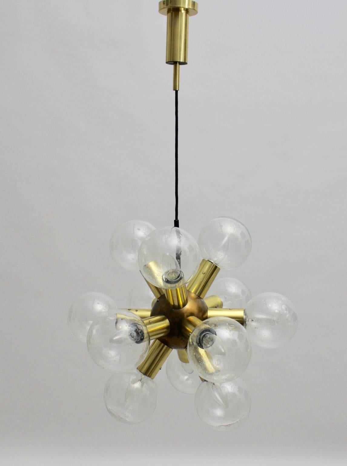 Mid Century Modern vintage sputnik chandelier from brass and glass by J.T.Kalmar.
The sputnik chandelier was designed and executed by the Viennese lighting firm J.T.Kalmar, 1970.
The atomic chandelier has twelve brass sockets E 14 and twelve