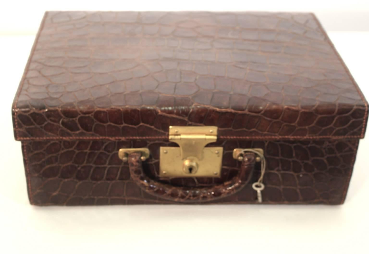 Art Deco alligator traveling grooming leather case is lined with red leather and features various compartments replete with glass bottles with gold lids, leather boxes, flacons and a mirror.
The leather case is lockable with the original key.

The