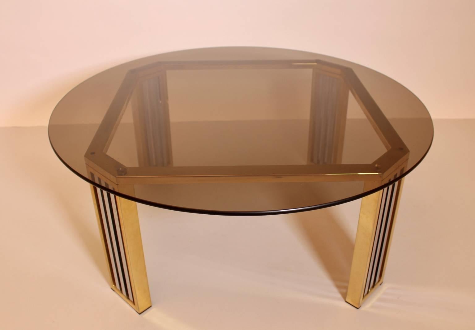 Il tavolino era realizzato in cromo e ottone.
La base ha bordi smussati e un piano rotondo in vetro fumé.

Il diametro del piano in vetro è di 91 cm.