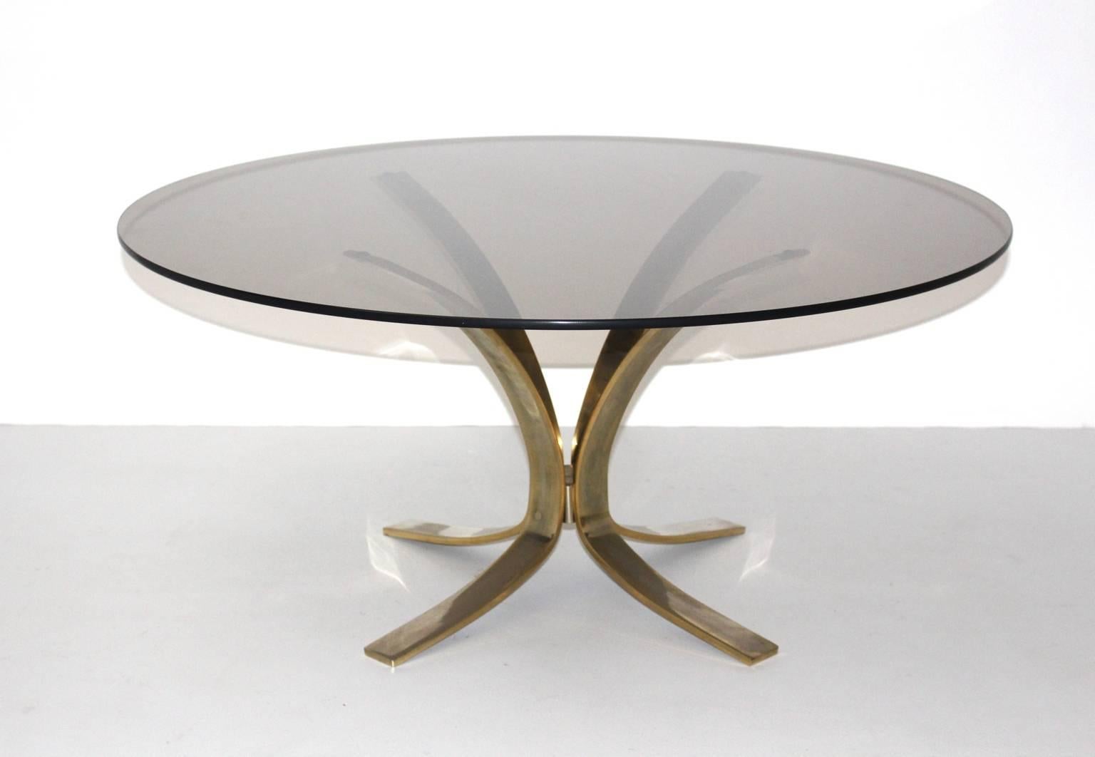 The coffee table was designed by Roger Sprunger 1960s, and produced by Dunbar Furniture, USA.

The coffee table has a brass-plated base and a round smoked glass top in very good condition with minor signs of age and use.
The base has a wonderful