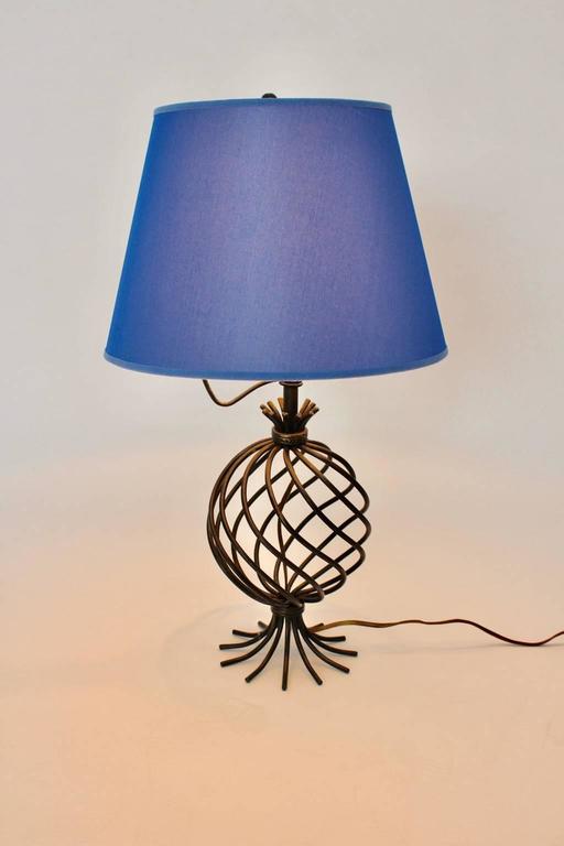 A mid century modern vintage metal table lamp, which shows a renewed blue textile fabric lamp shade and a round metal black lacquered base.

The table lamp lights with one E 27 bulb and has an on/off switch.
All measures are approximate.