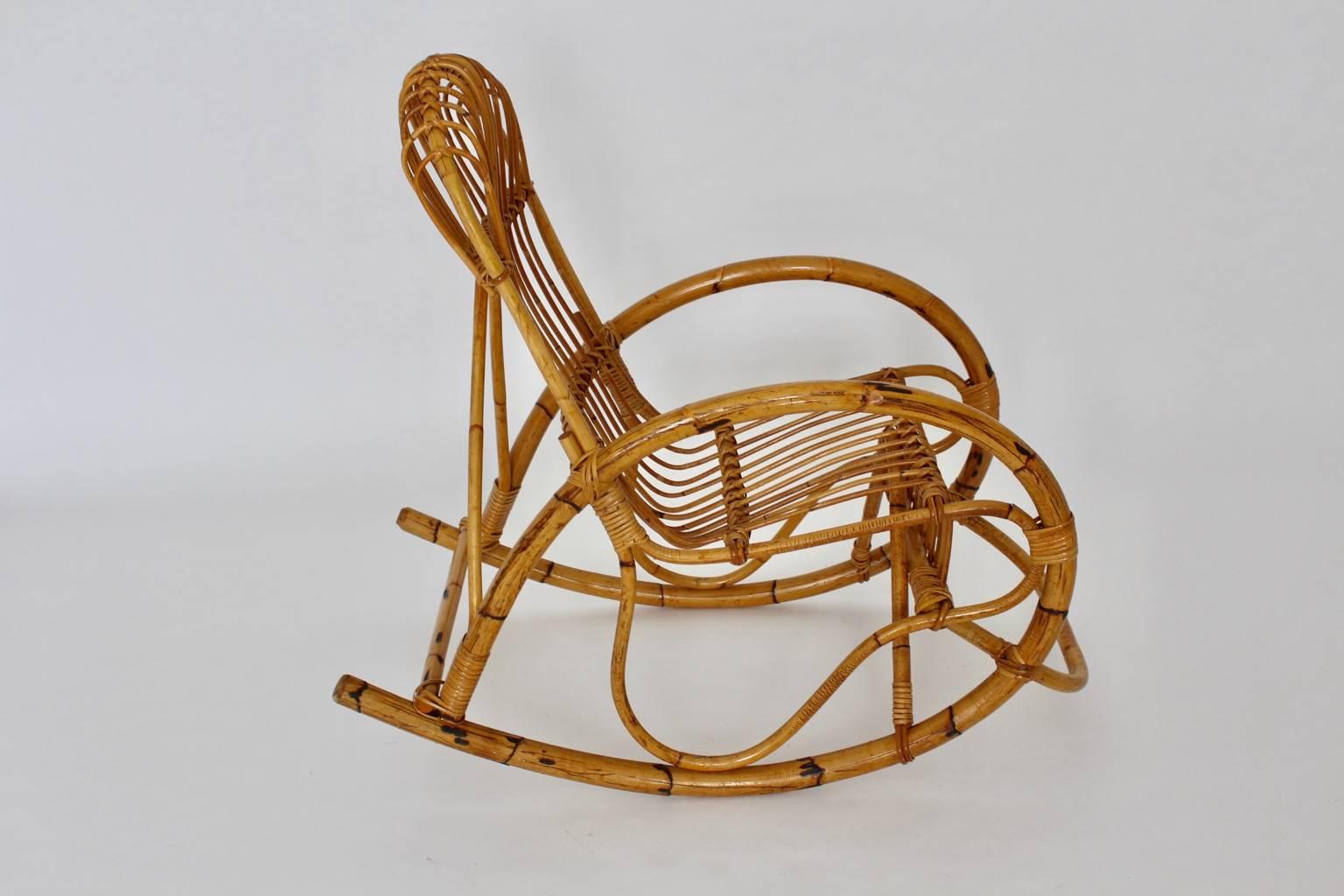 Fauteuil à bascule organique vintage de style Riviera en bambou rotin Italie années 1960.
Le rocking-chair sculptural présente une forme superbe avec des accoudoirs incurvés de forme ovale, qui se fondent dans la roue à tige de bambou, tandis que la