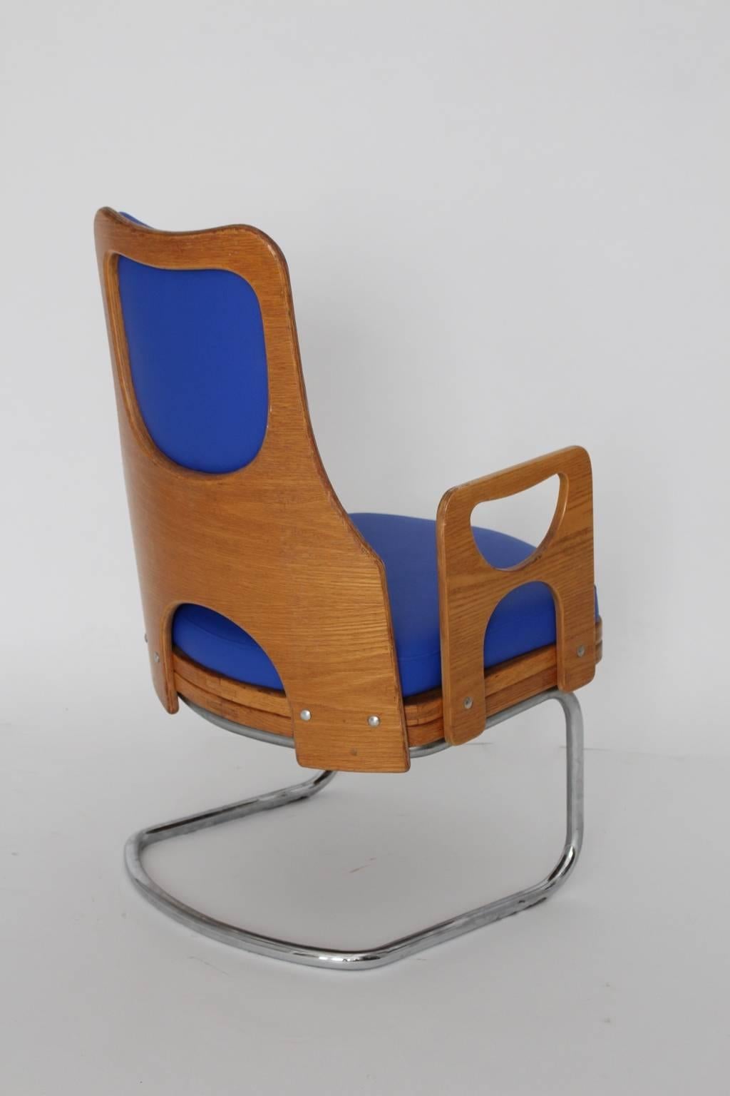 Space Age vintage blue armchair or lounge chair or club chair from teak plywood and chromed tubular steel.
The upholstery is covered with faux leather in bold blue color tone, which reminds on cornflowers.
Very good condition with minor signs of age