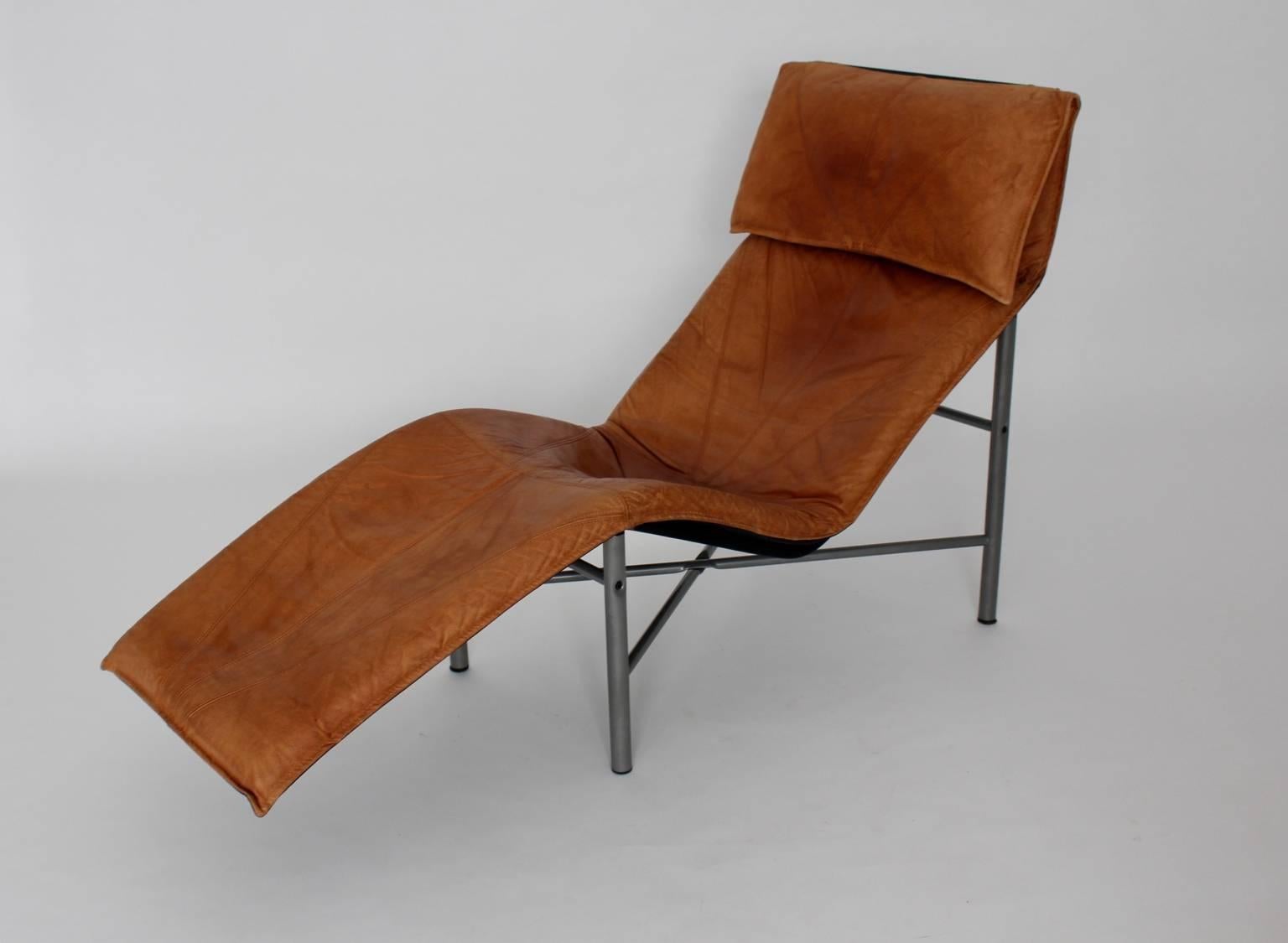 This very comfortable and very stabile chaise longue designed by Tord Bjorklund has a great leather patina.
The tube steel base is grey lacquered and the cognac leather upholstery lies on and is removable.