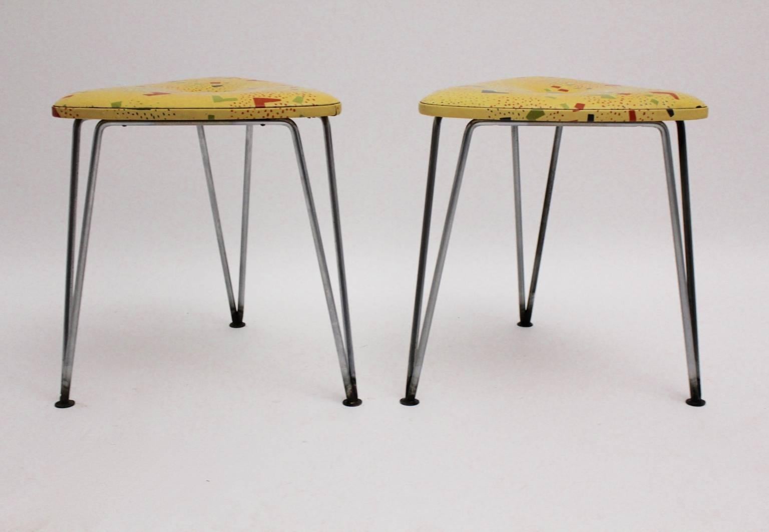 Mid century modern vintage pair of three-legged stools with ametal base and a plastic covered seat.
The stools have a seat from plastic cover with multicolored geometric pattern and pin legs.
The condition is good with signs of age and use, like