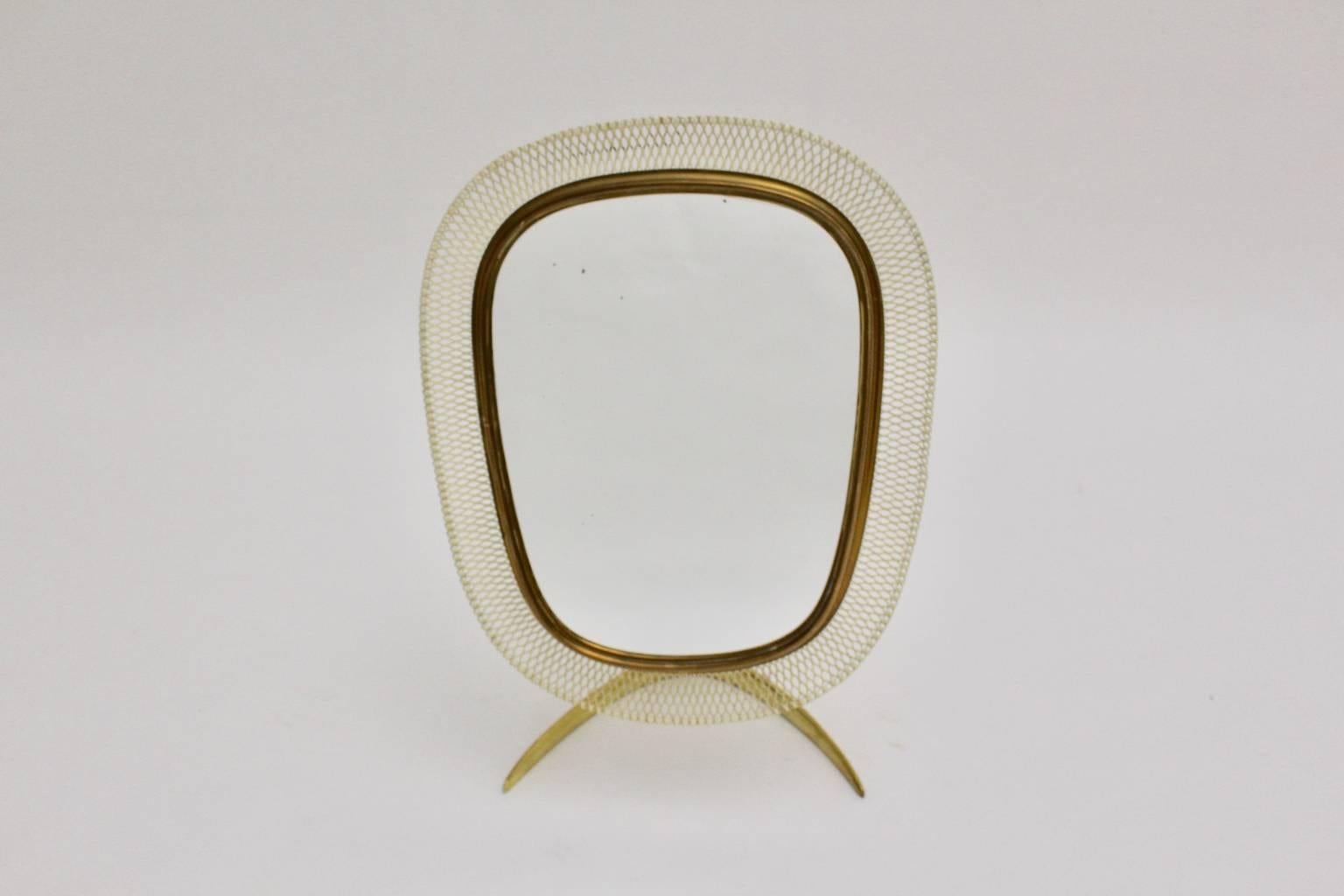 Miroir de table Mid Century Modern composé d'un pied en laiton massif et d'un miroir réglable arrondi avec un cadre en laiton et un fil de maille laqué blanc.

Le dos de ce miroir de table est recouvert d'un tissu blanc ivoire, il présente quelques